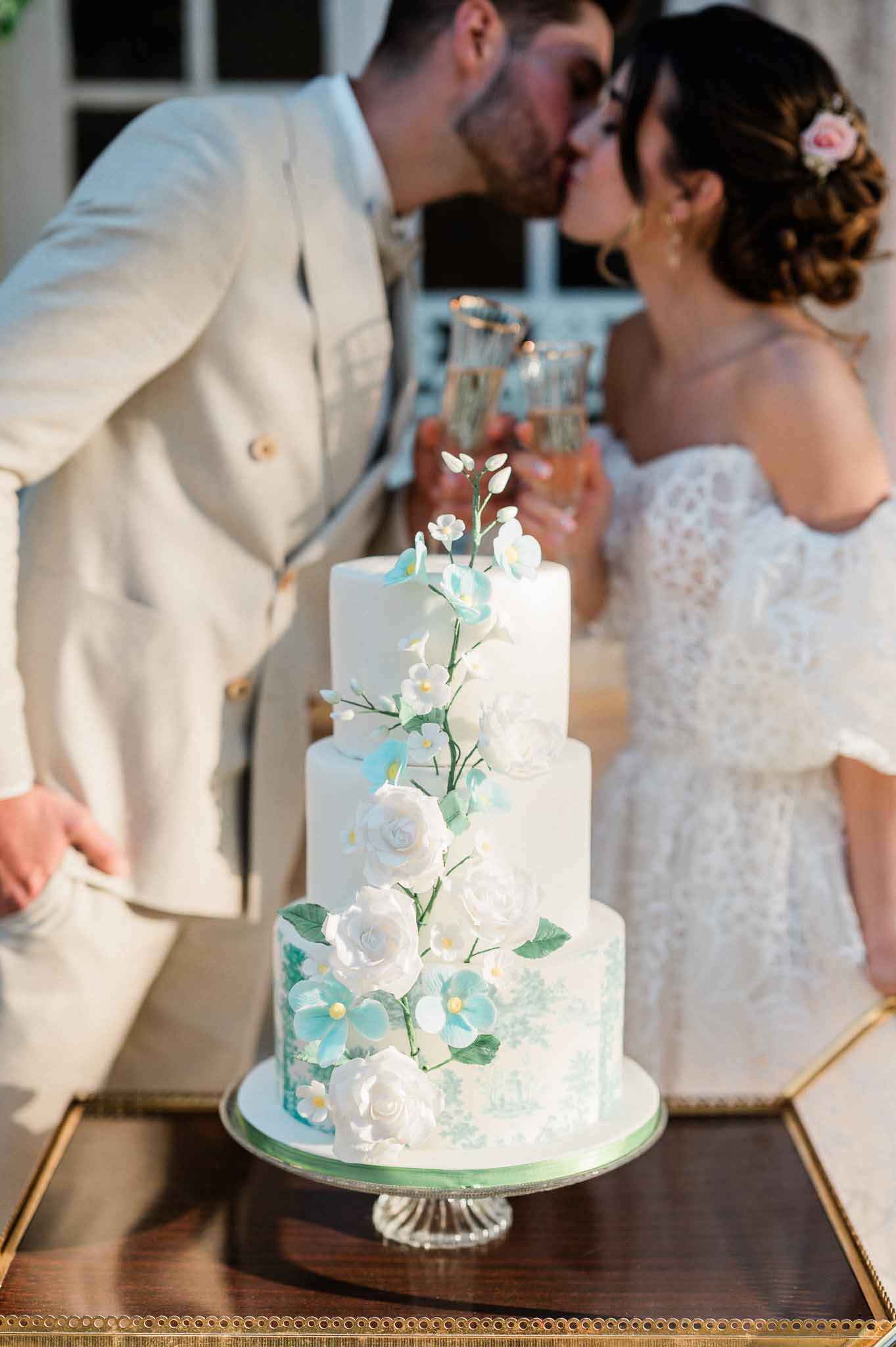 Bride and groom cutting three-tiered wedding cake at indoor reception venue