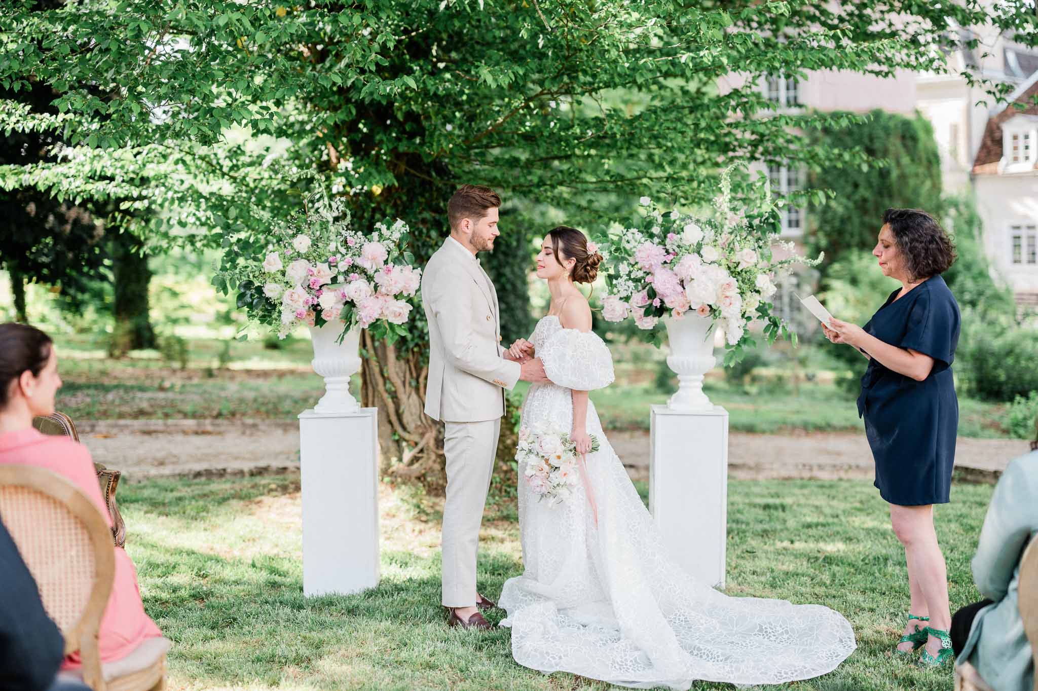 Bride and groom exchanging vows during outdoor garden ceremony with floral arbor