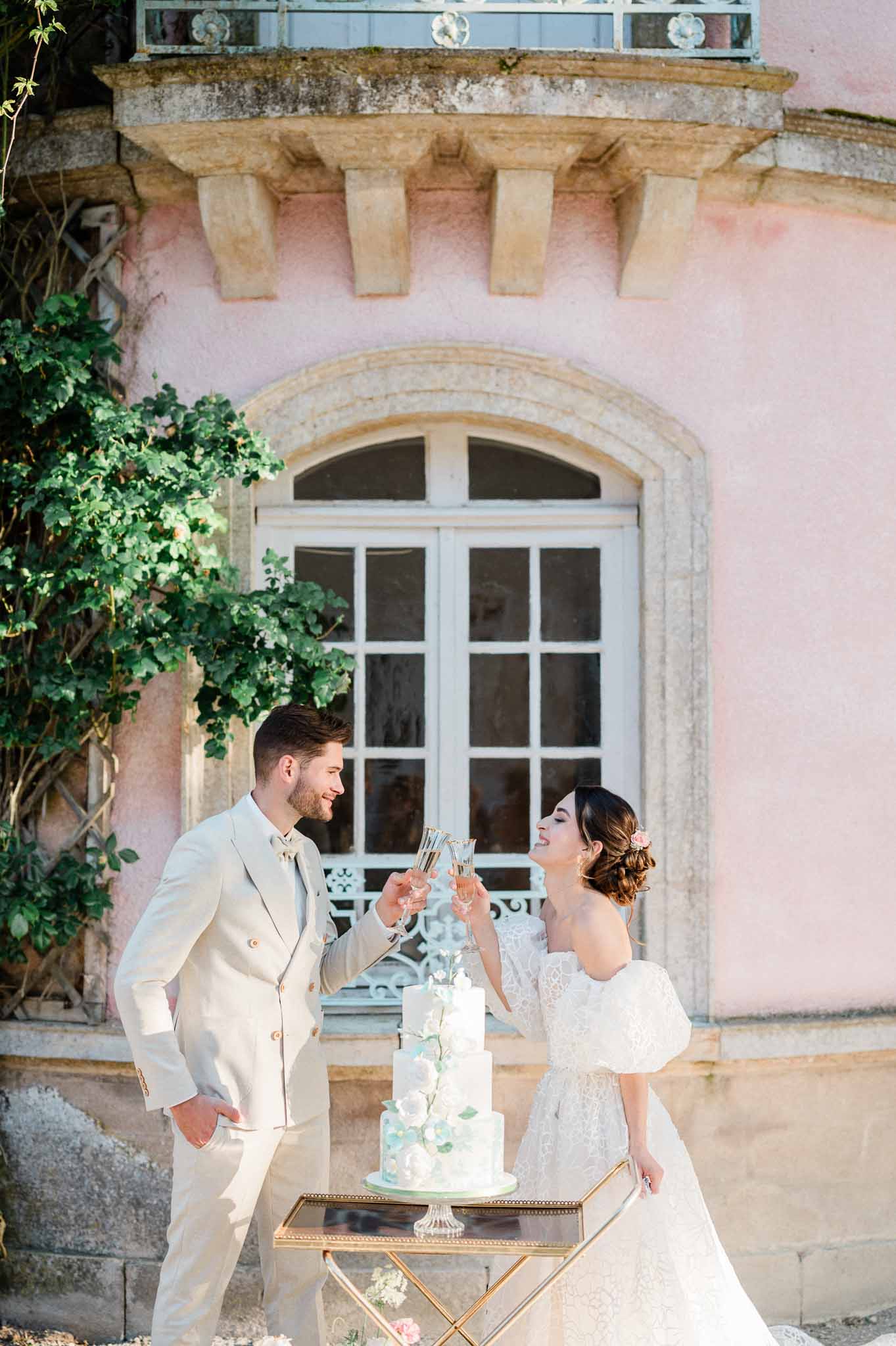 Bride and groom toasting during cake cutting at European courtyard wedding venue