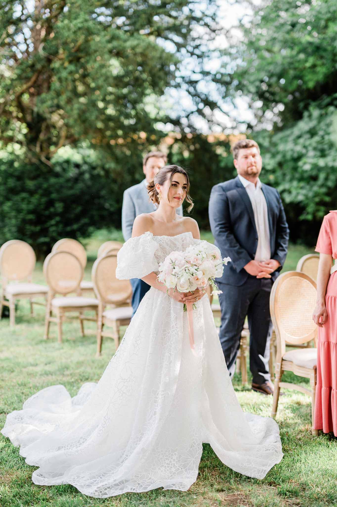 Bride and groom during outdoor garden wedding ceremony with guests seated in wooden chairs