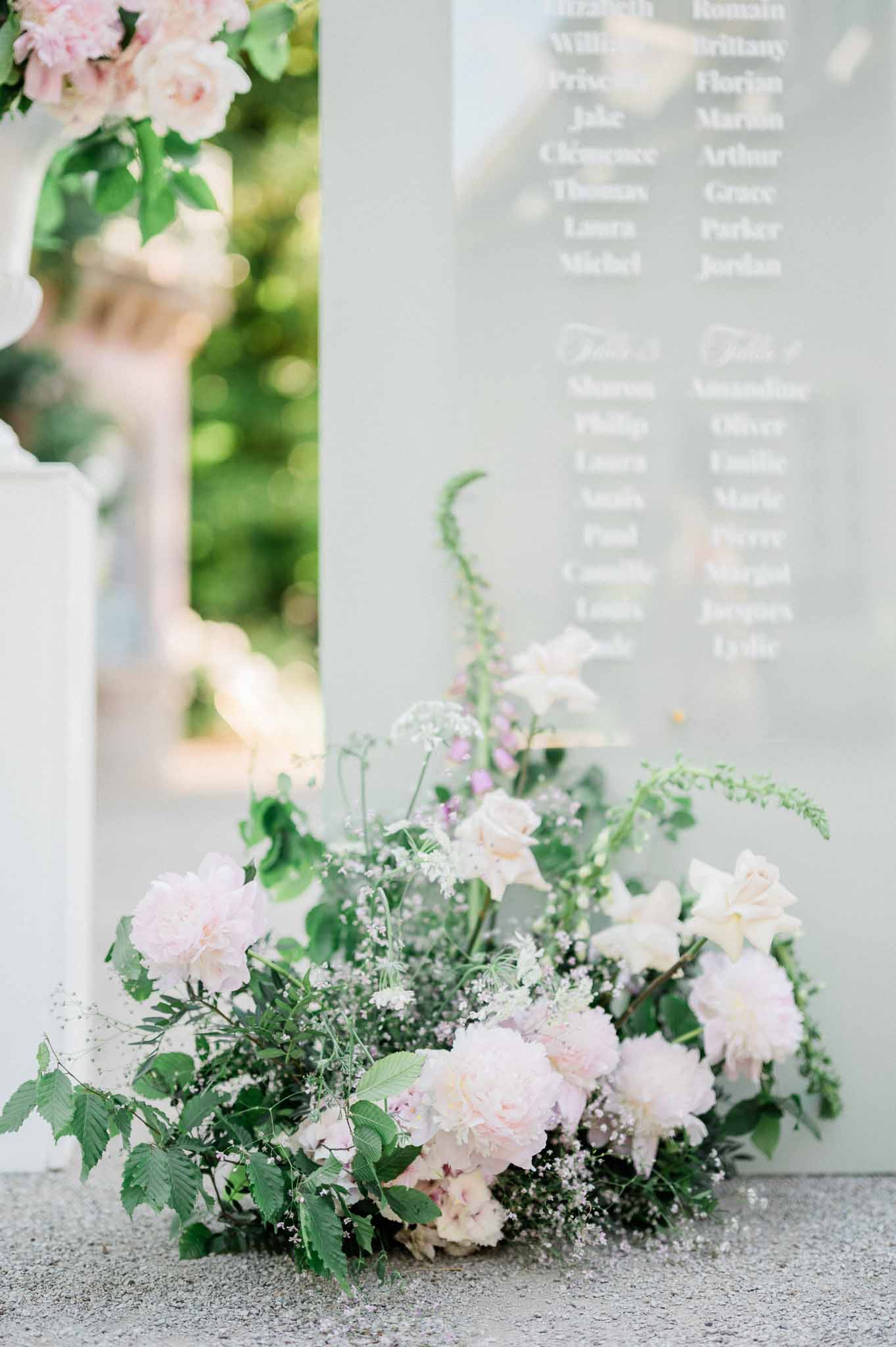Wedding floral arrangements and seating chart display at outdoor garden reception venue