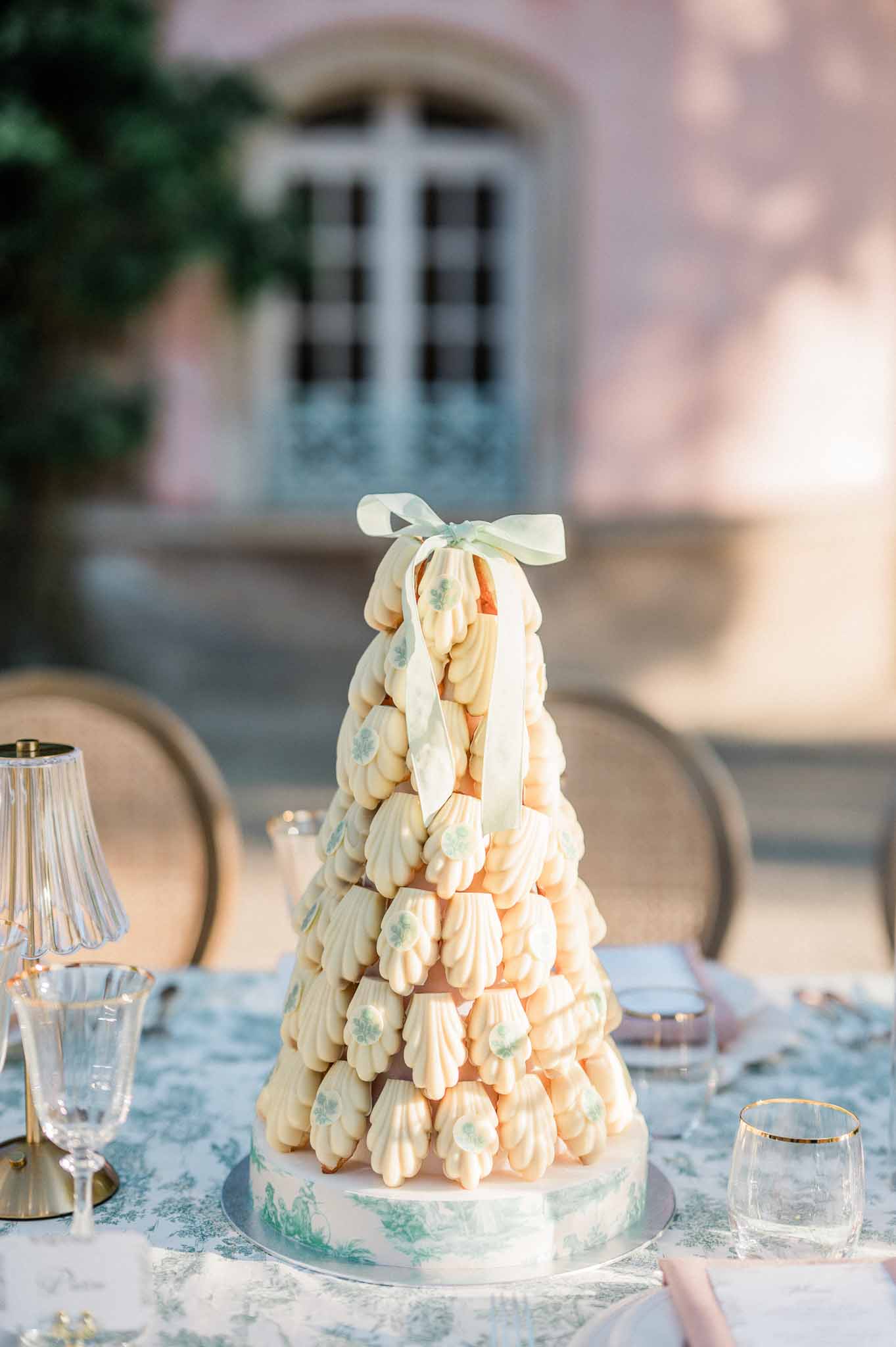 Cream and peach croquembouche tower on botanical print linens at outdoor Mediterranean reception