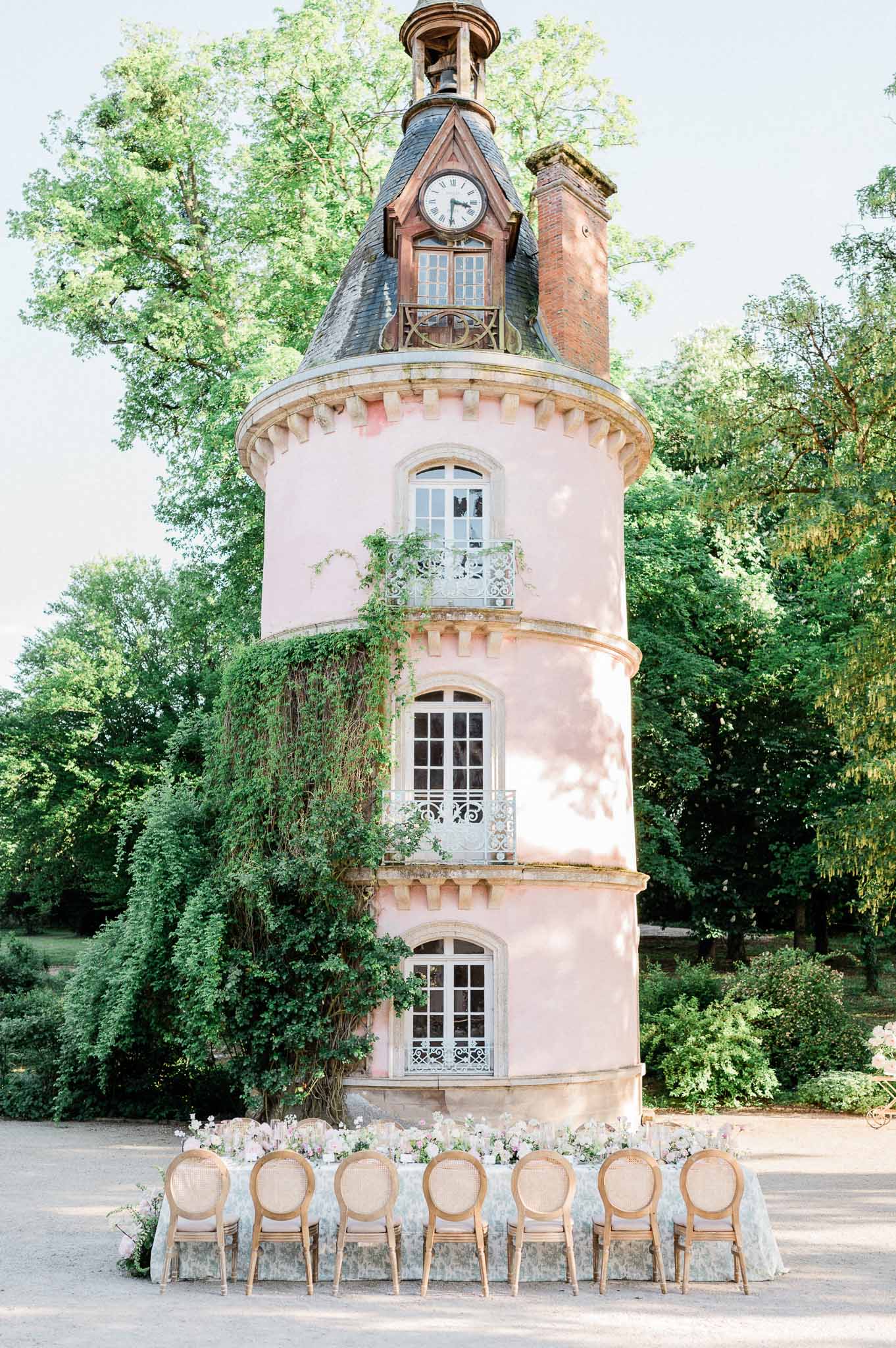 Historic pink tower venue with ceremony seating and floral arrangements in garden setting