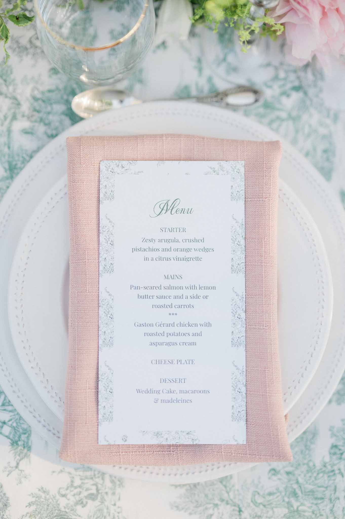 Wedding reception table place setting with menu card, dusty rose napkin, and turquoise damask linen
