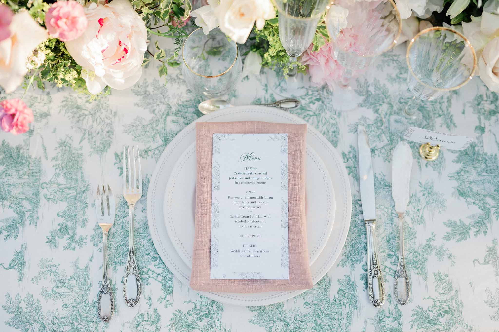 Elegant place setting with sage toile linen, dusty rose napkin and floral centerpiece at wedding reception