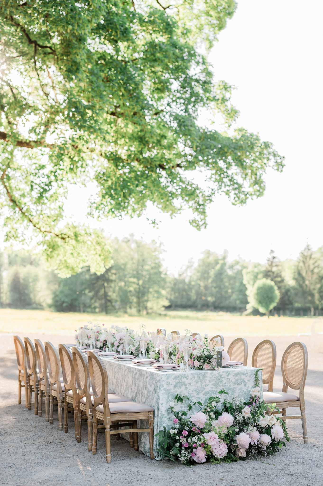Outdoor reception table setup with floral centerpieces in garden courtyard setting