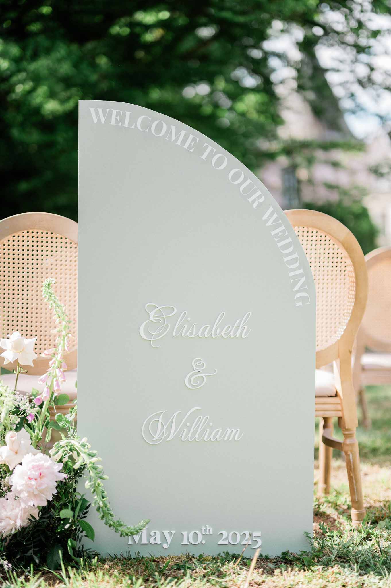 Sage green welcome sign with couple names and wedding date at garden ceremony entrance