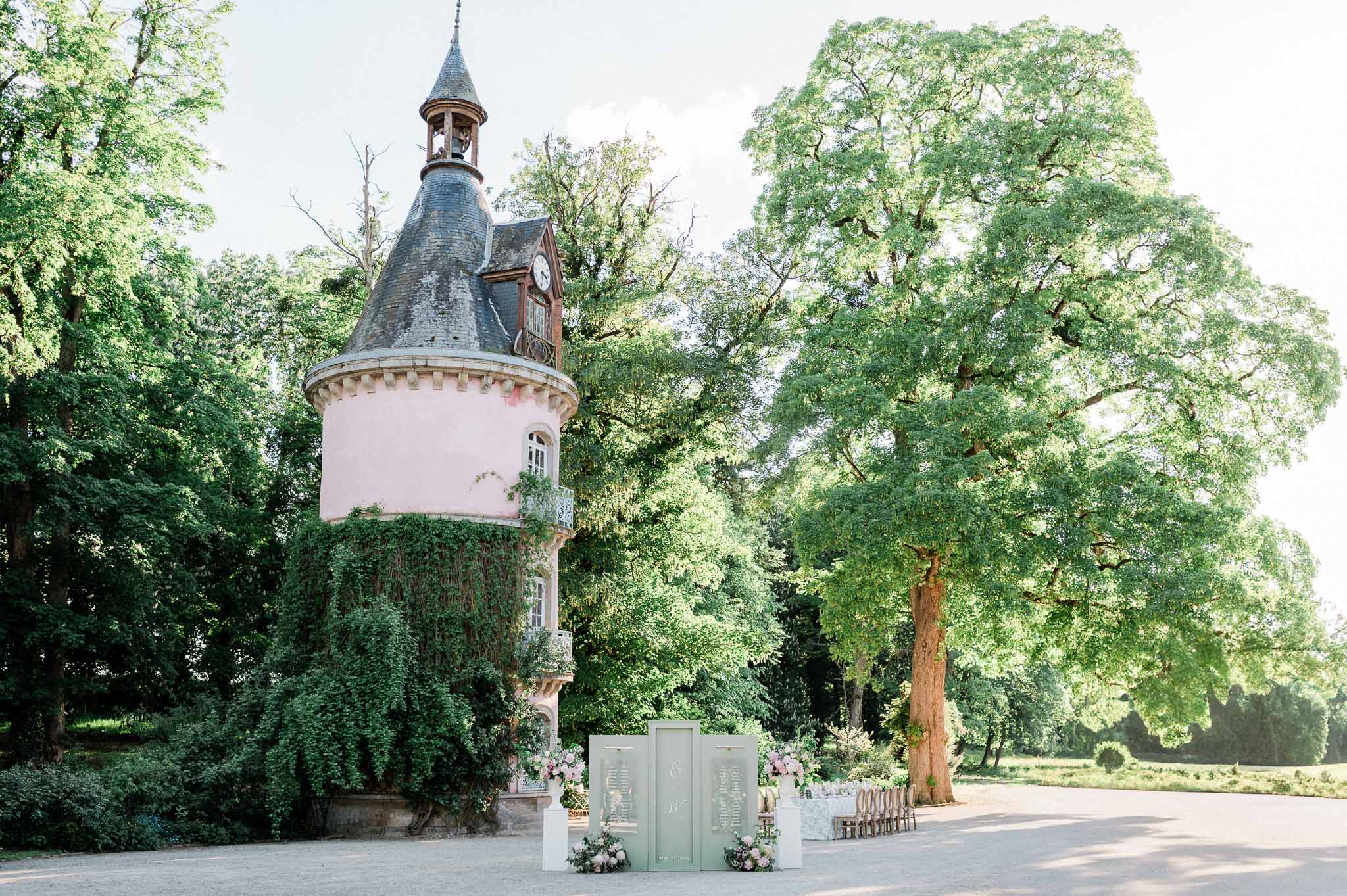 Wedding ceremony setup with pink stone château tower and floral arch in historic courtyard venue