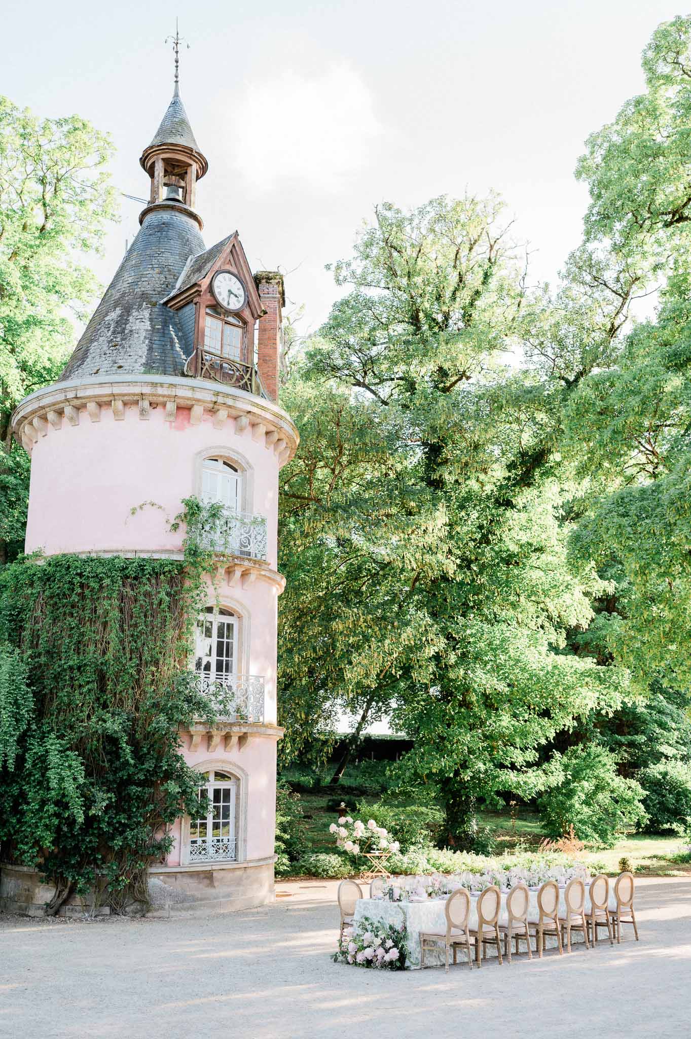 Historic pink tower courtyard ceremony setup with Chiavari chairs and white floral altar arrangement