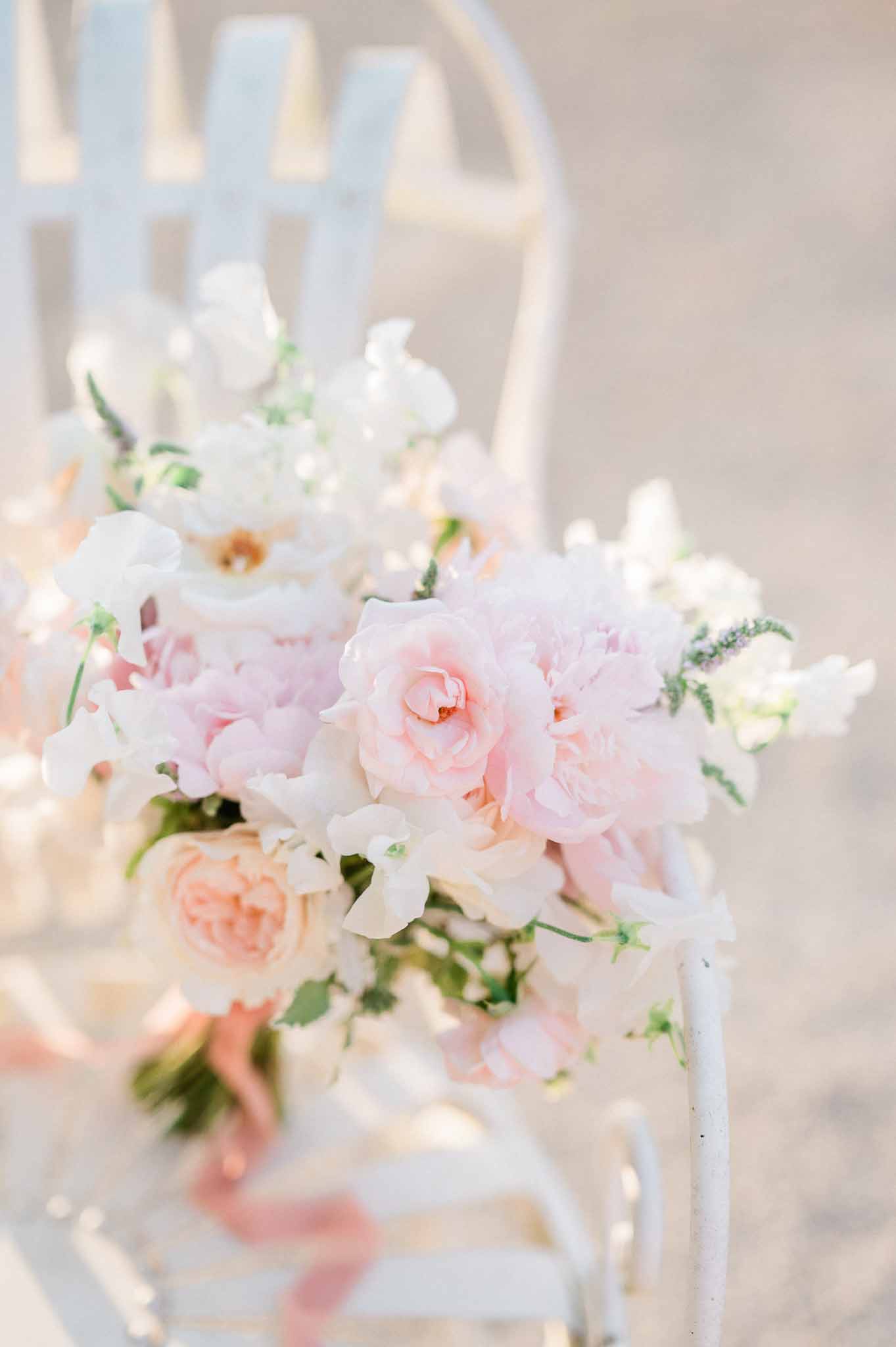 Bridal bouquet with blush roses and sweet pea flowers at outdoor wedding venue