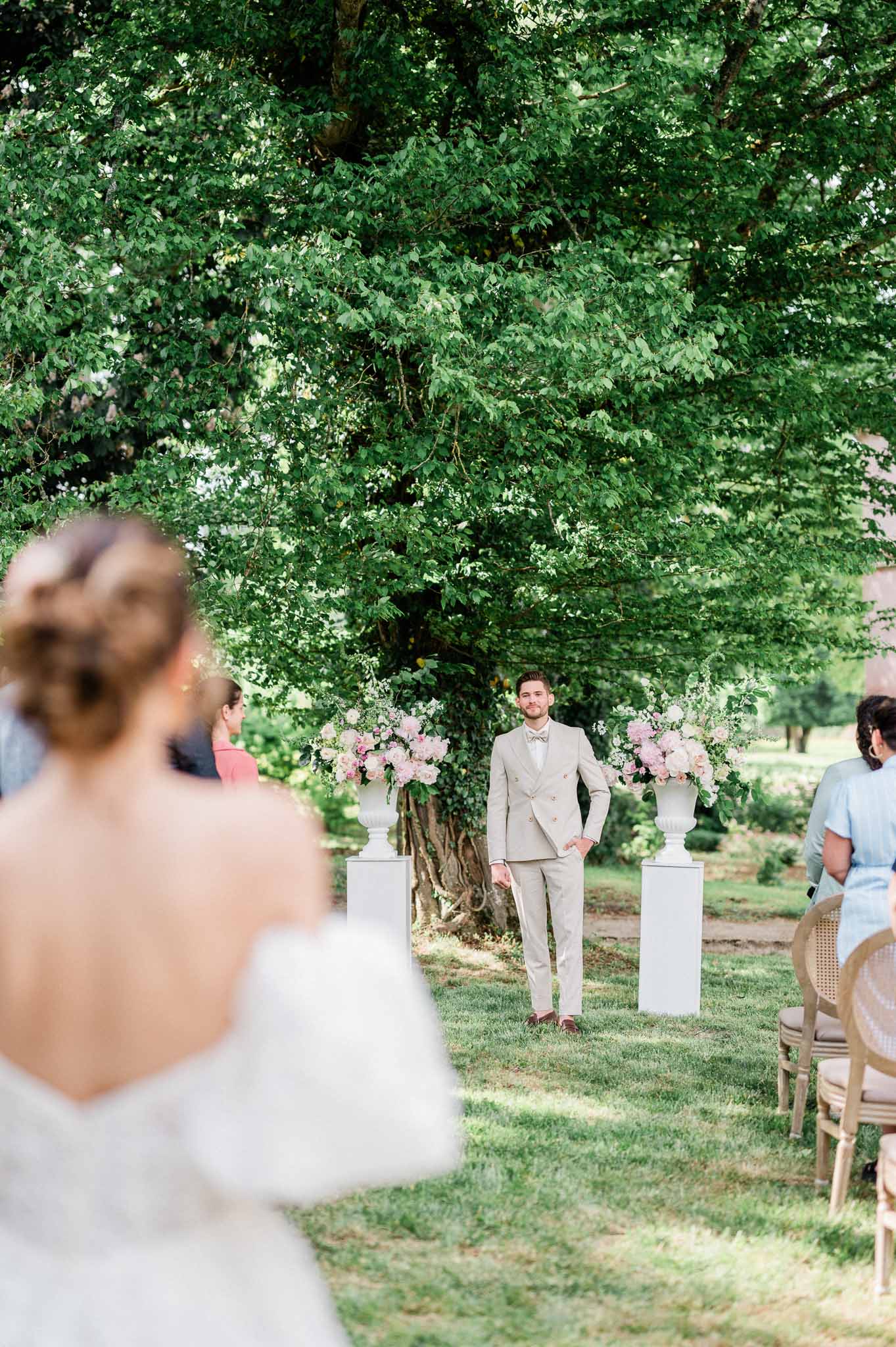 First look moment between bride and groom in outdoor garden ceremony setting with floral arrangements