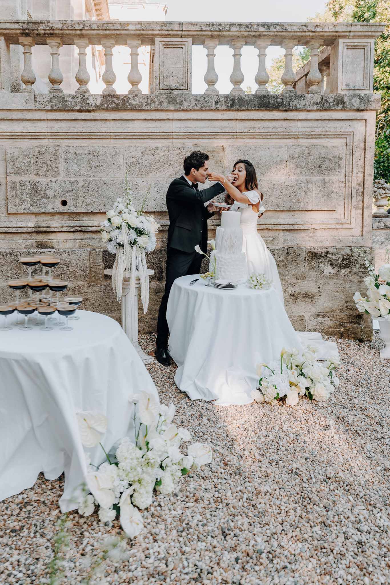 Cake cutting beside three-tier white cake with calla lily arrangement and espresso martini tower at chateau