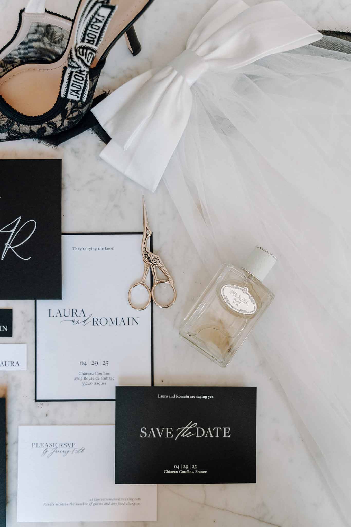 Monochrome stationery suite with J'Adior slingback heels, black lace lingerie, and tulle bow veil on marble