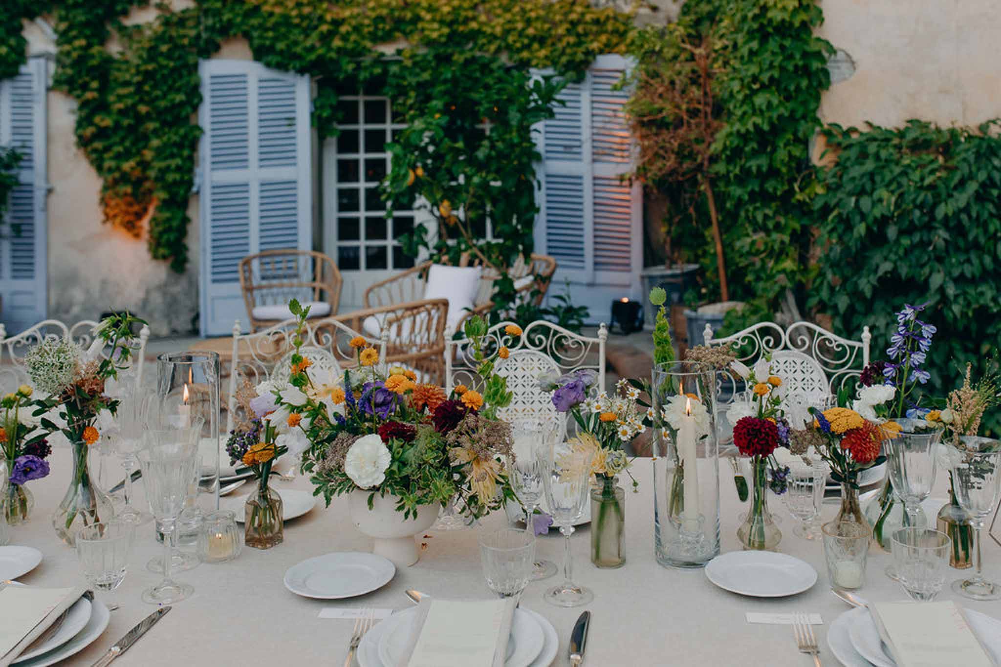 Courtyard reception table with wildflower centerpiece of marigolds dahlias and delphiniums