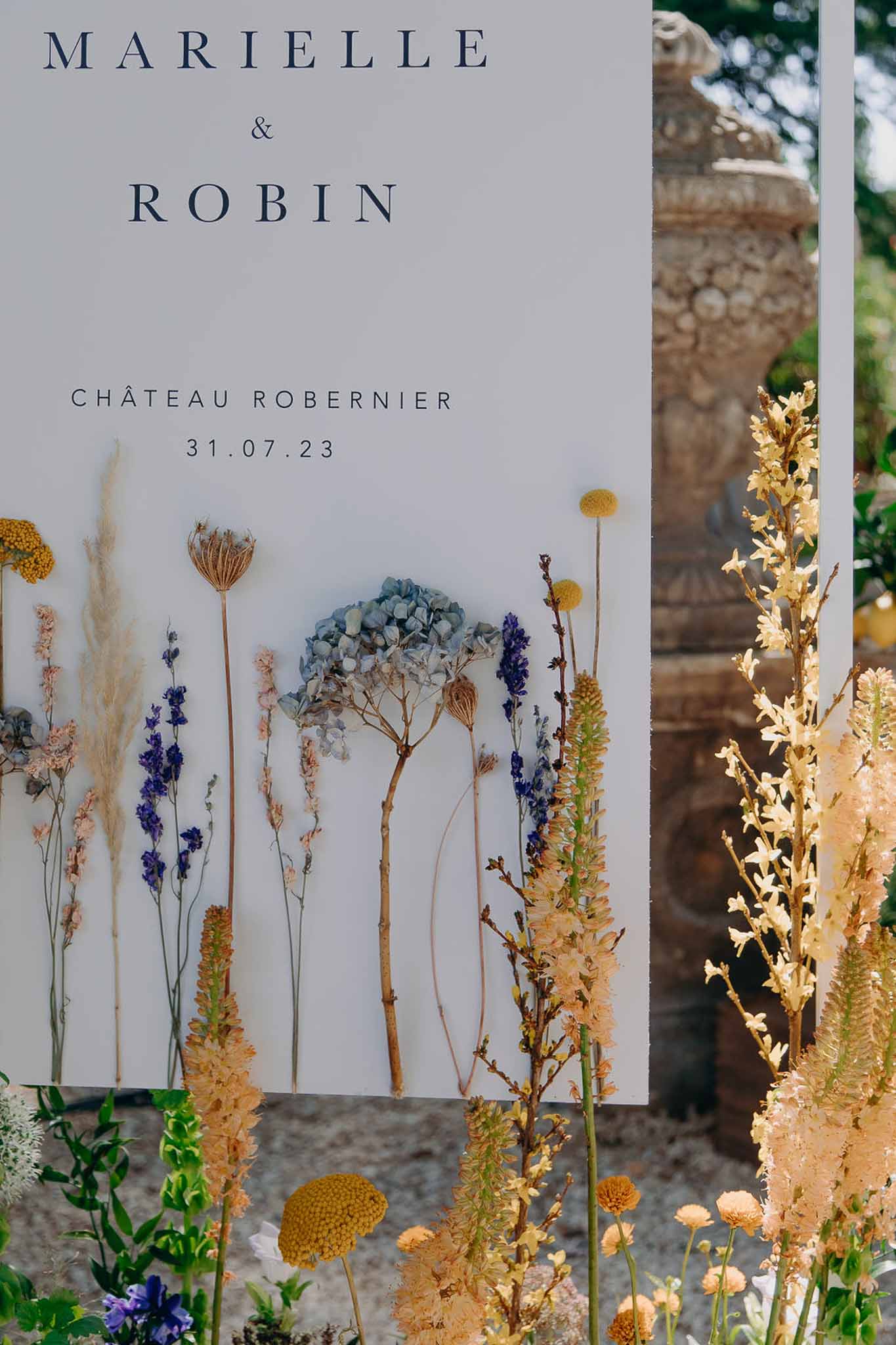 Wedding welcome sign for Chateau Robernier decorated with dried hydrangea, lavender, pampas grass, and craspedia