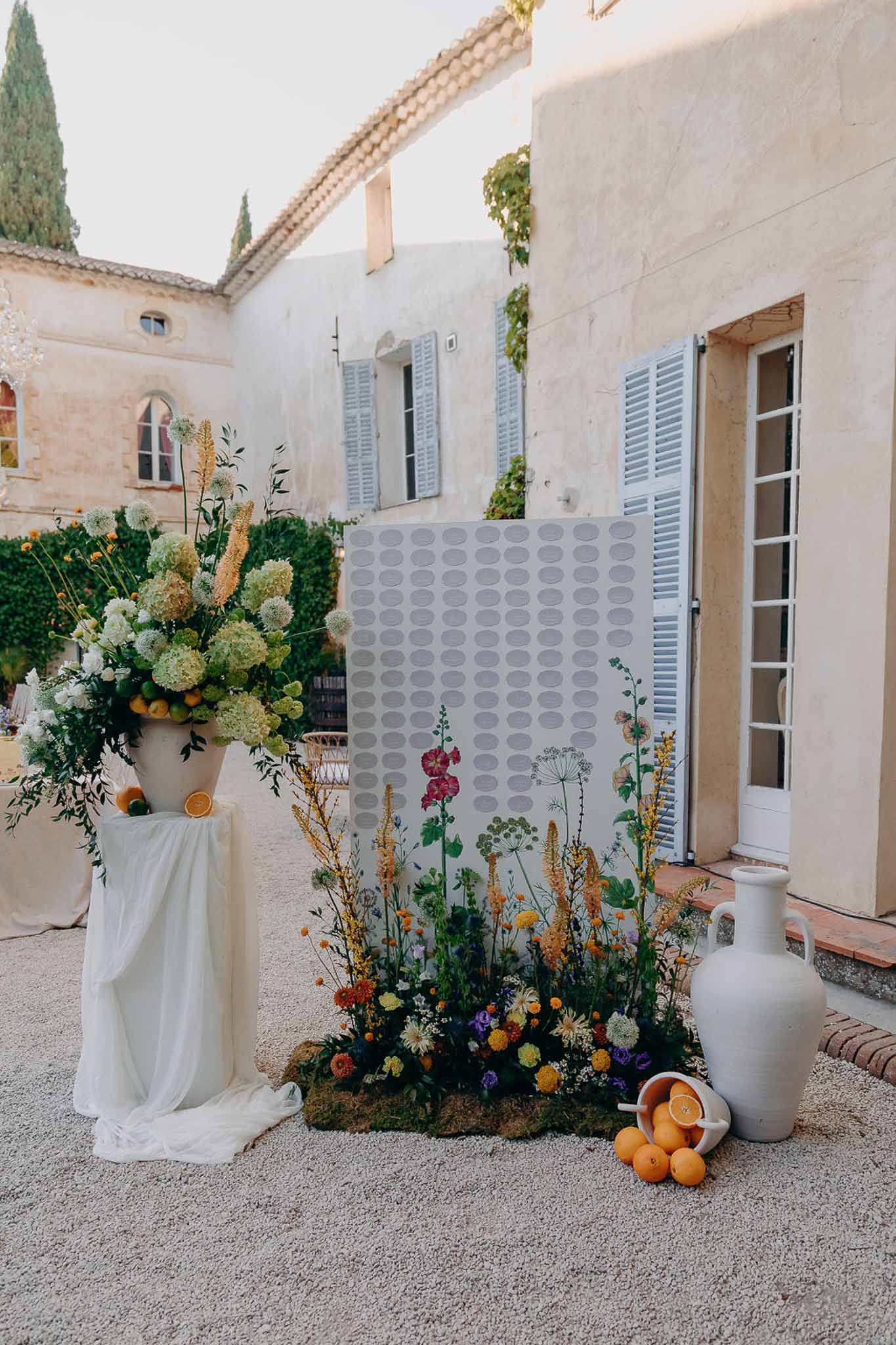 Seating chart with wildflower illustration, marigold and purple ground display, and citrus-accented hydrangea urn