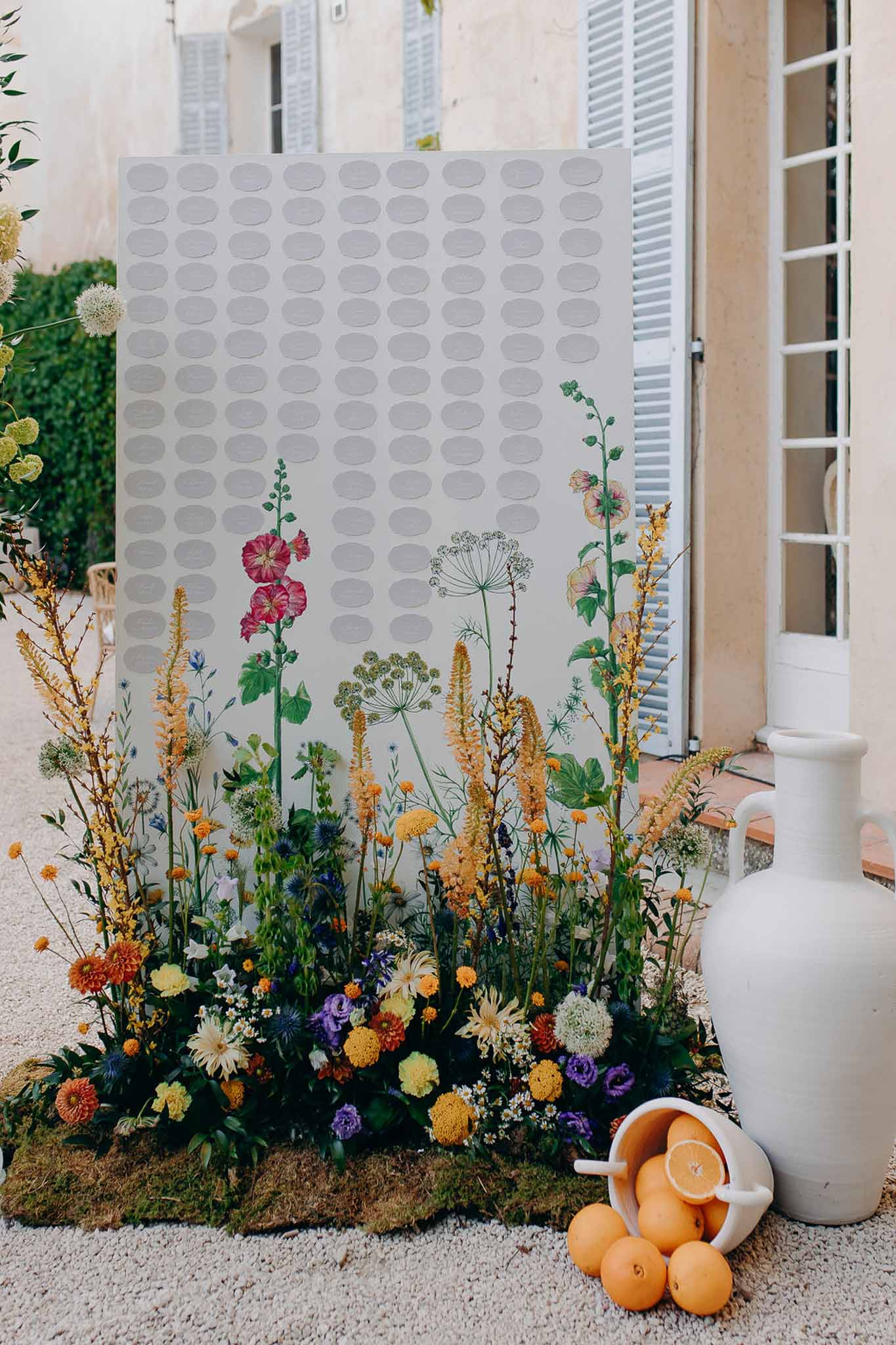 Botanical seating chart with wildflower illustration and matching fresh flower installation at base