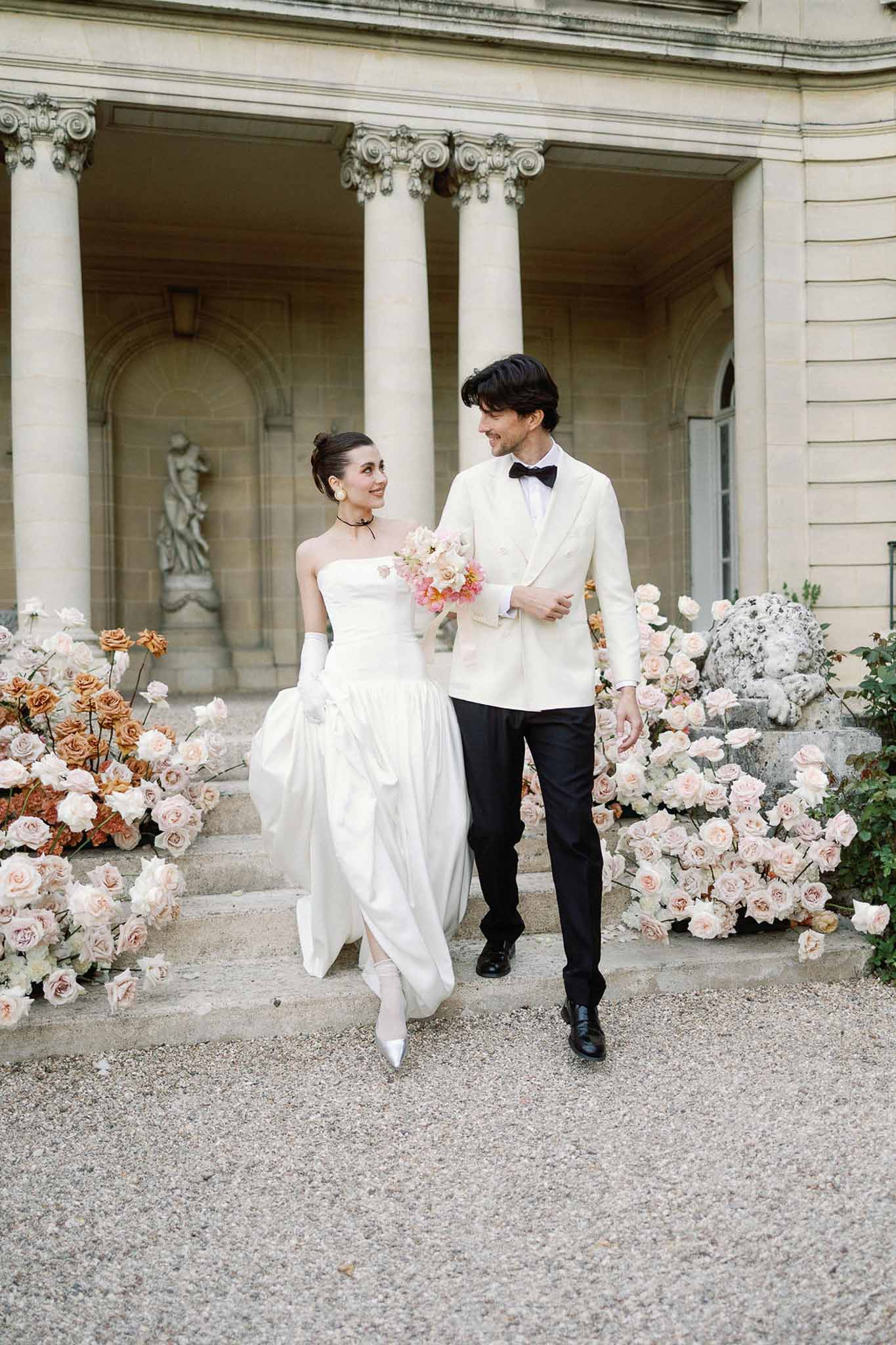 Bride and groom walking hand in hand in a garden