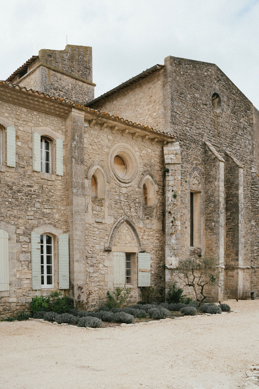 Historic stone building exterior with Romanesque architecture and Mediterranean courtyard landscaping