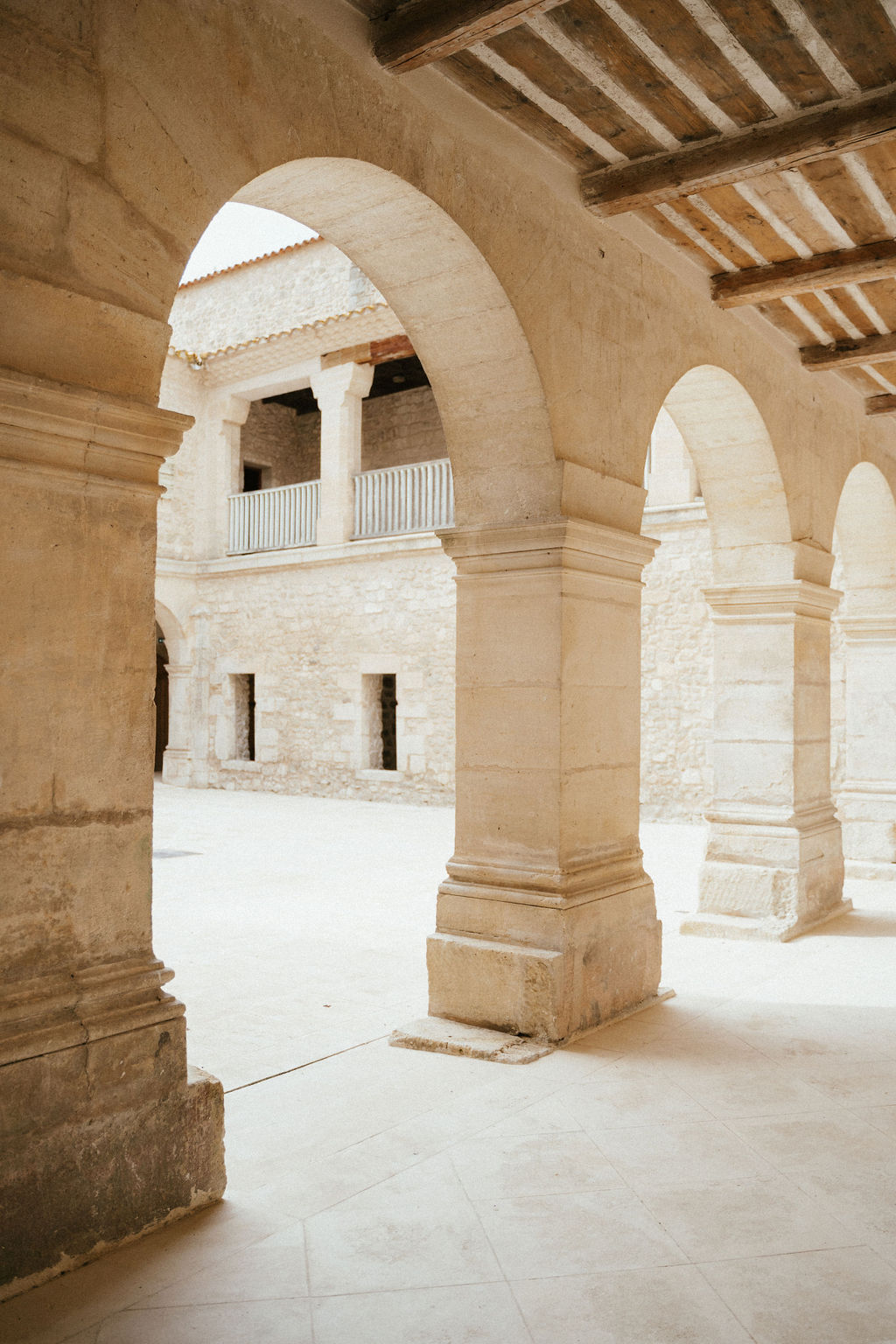 Historic stone colonnade with arches and columns at wedding venue interior