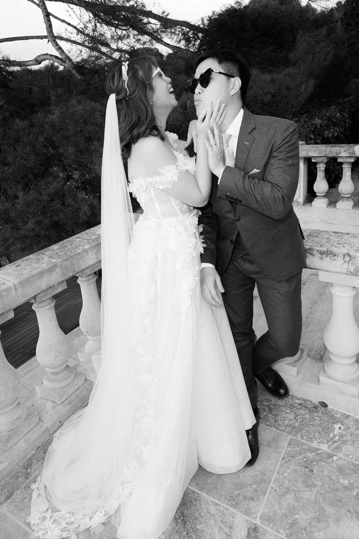 Black and white playful couple portrait with bride in floral applique gown and groom in heart sunglasses