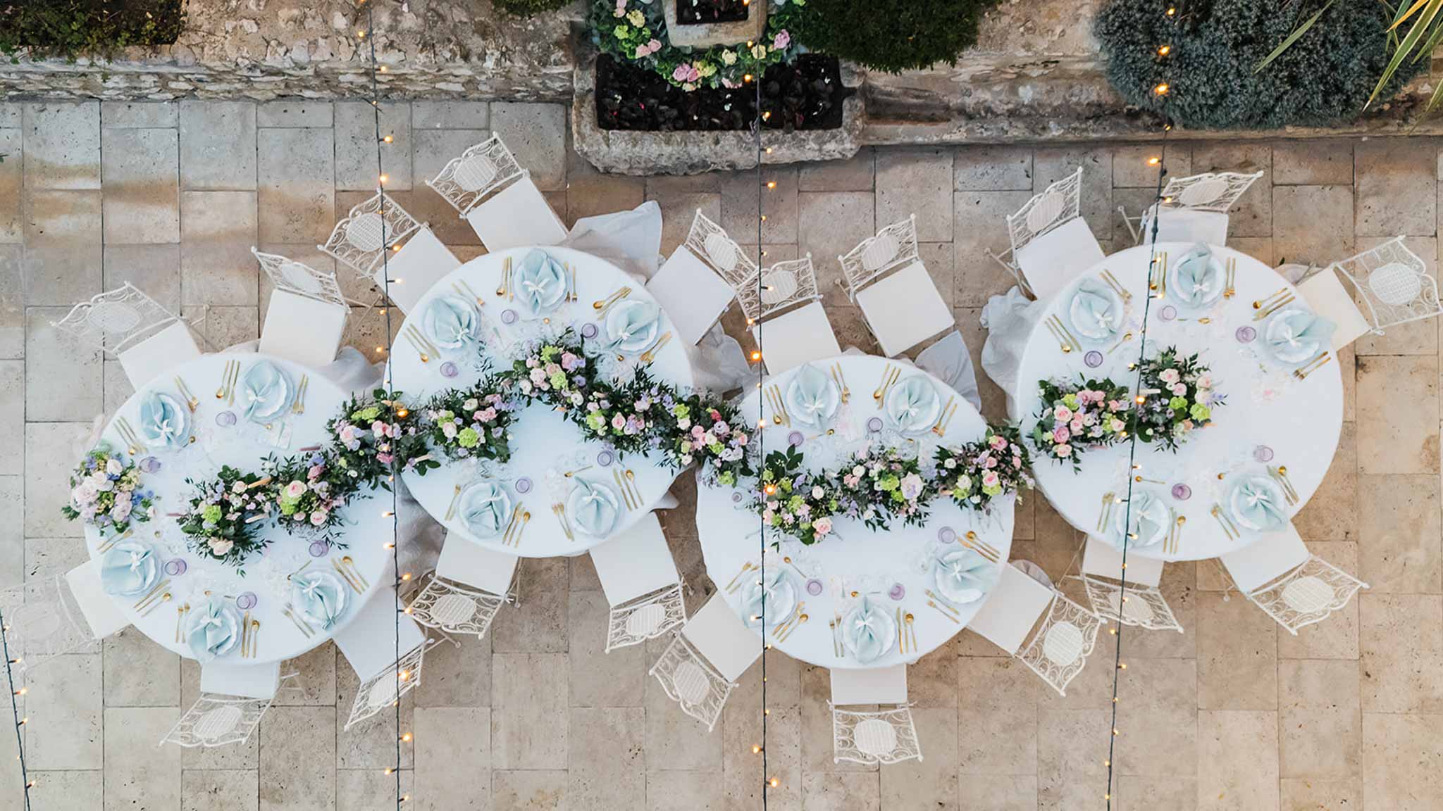 Aerial view of courtyard reception table settings with floral centerpieces and Mediterranean stone terrace