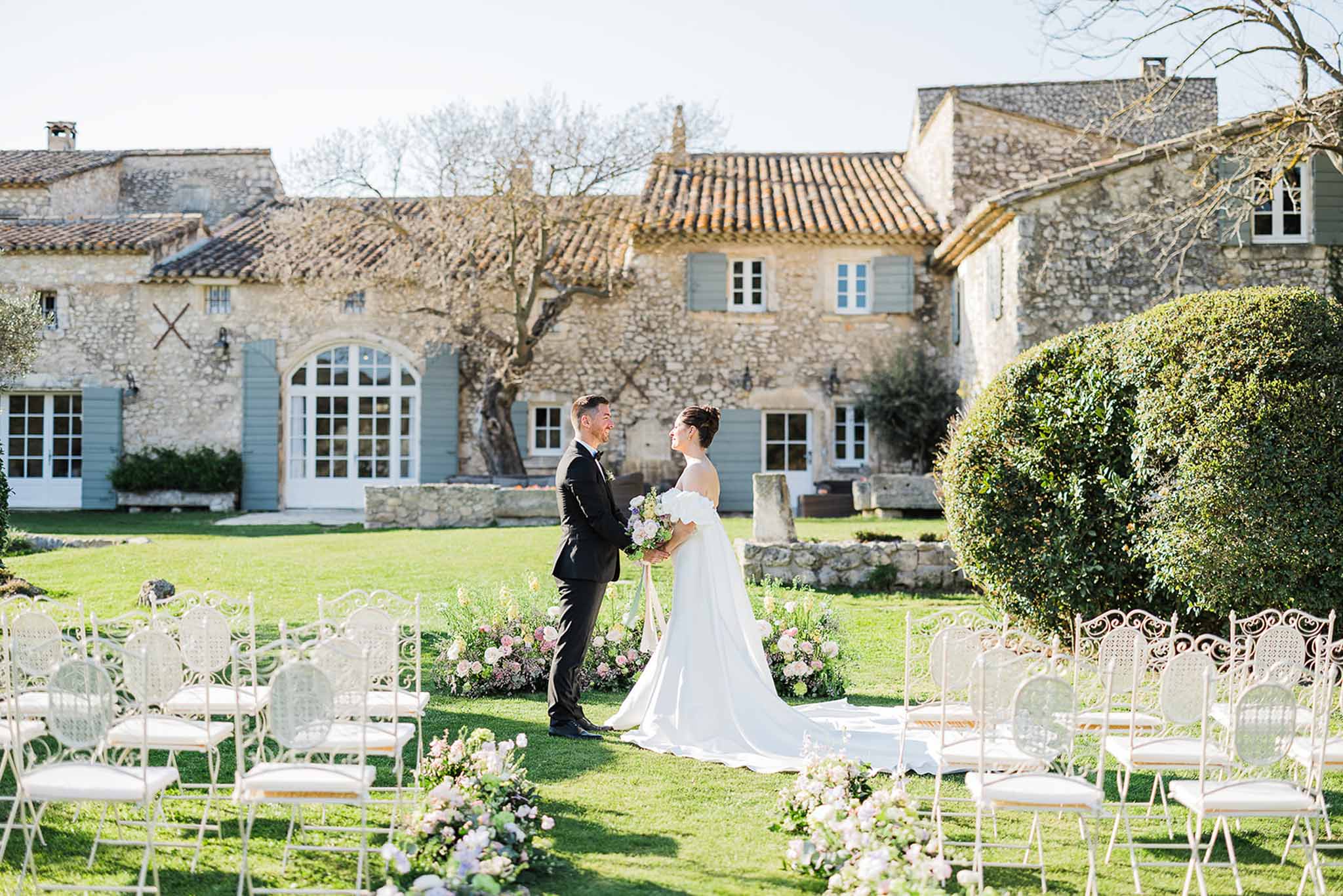 Bride and groom during outdoor ceremony at Provençal manor house courtyard with stone architecture