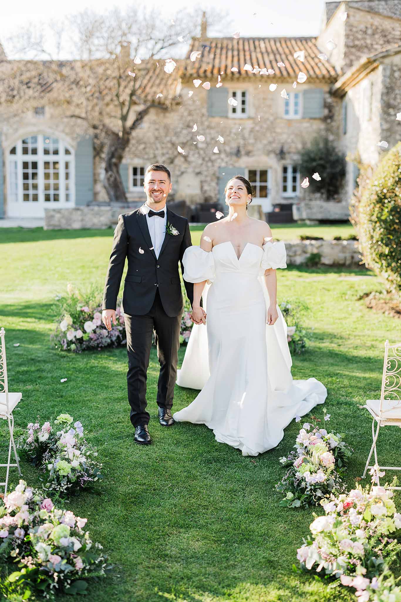 Bride and groom walking through garden courtyard recessional at stone manor wedding venue