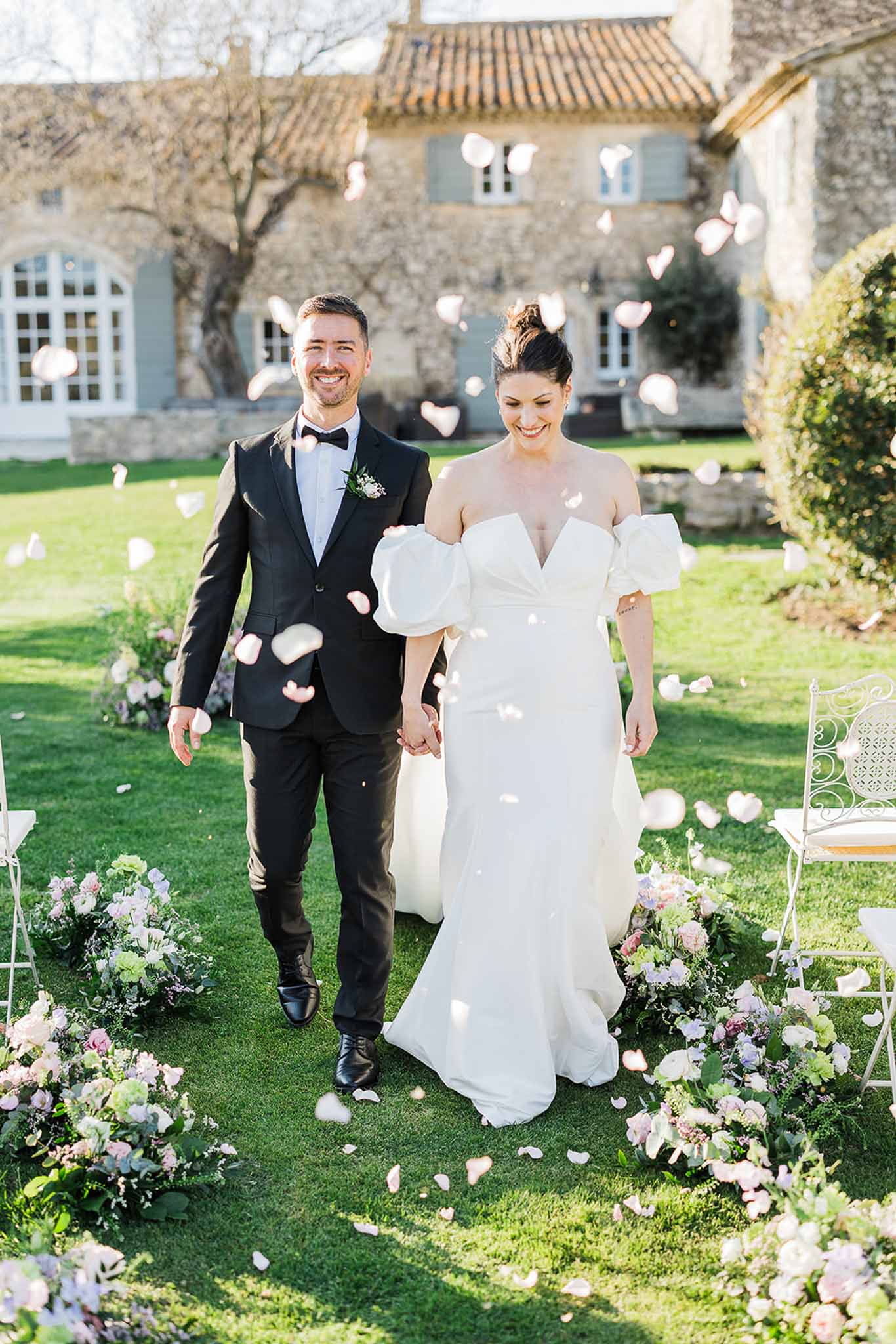 Bride and groom walking down aisle after ceremony at historic stone manor with courtyard