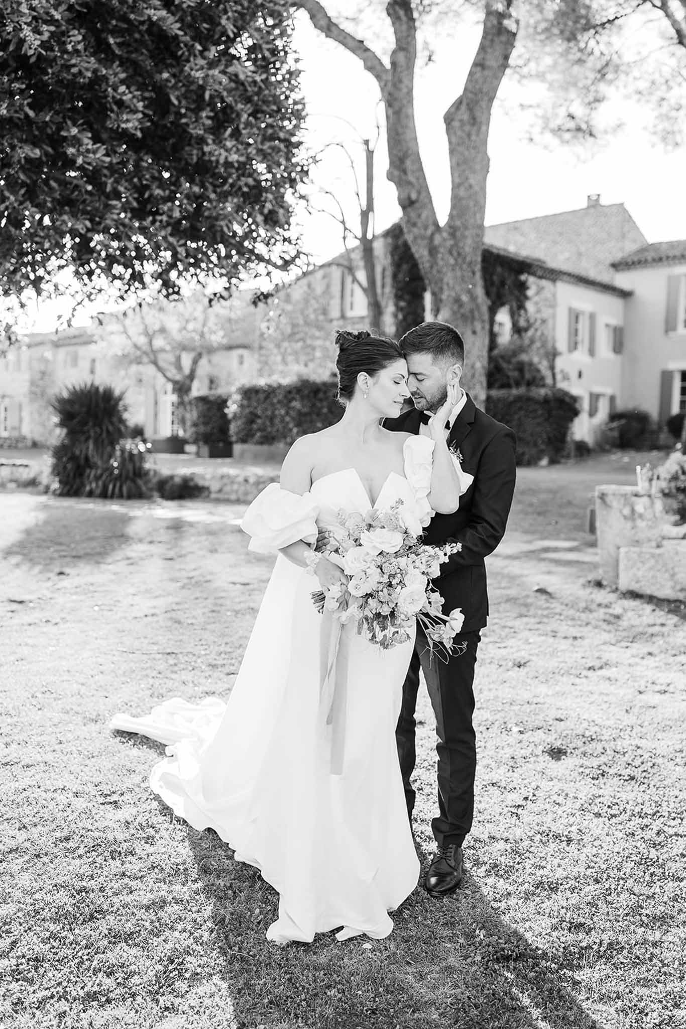 Bride and groom in intimate embrace on gravel pathway at Mediterranean villa courtyard