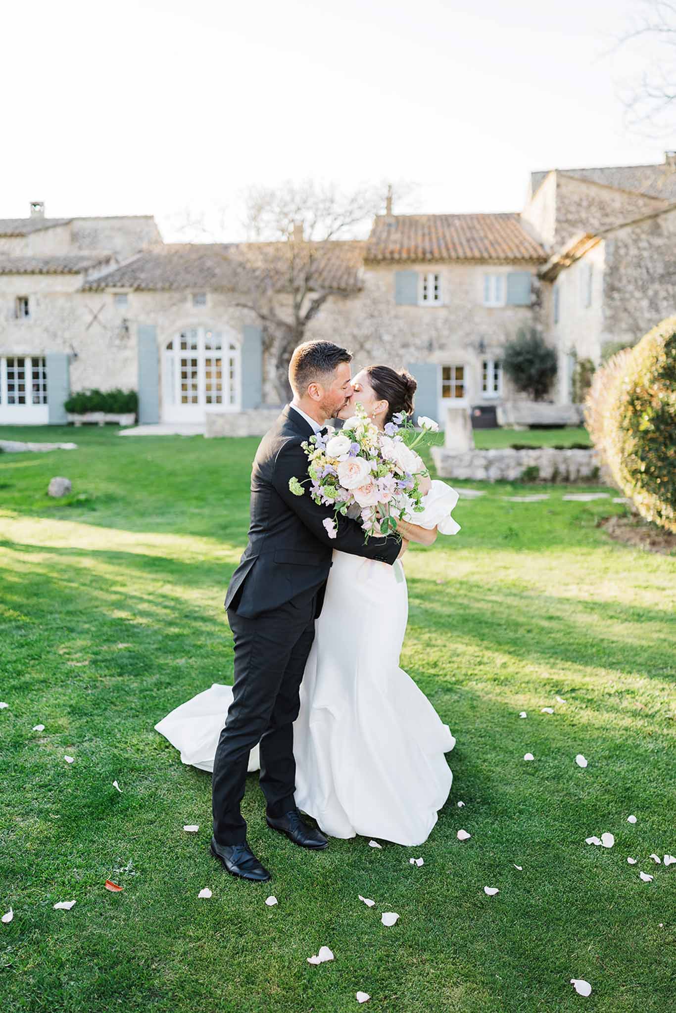 Bride and groom kissing on lawn at French château wedding venue