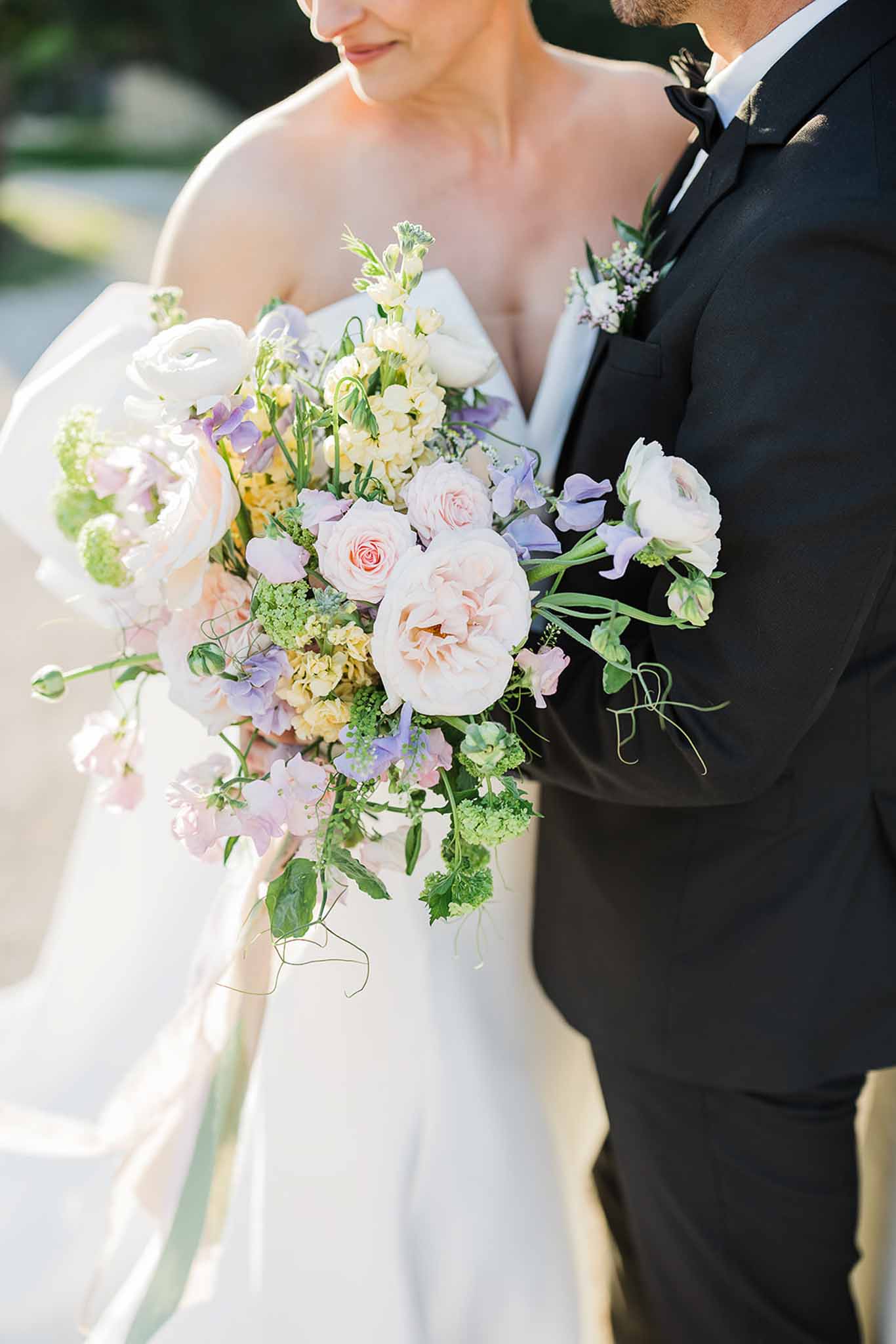 Bride and groom close-up portrait with bridal bouquet at outdoor garden wedding venue