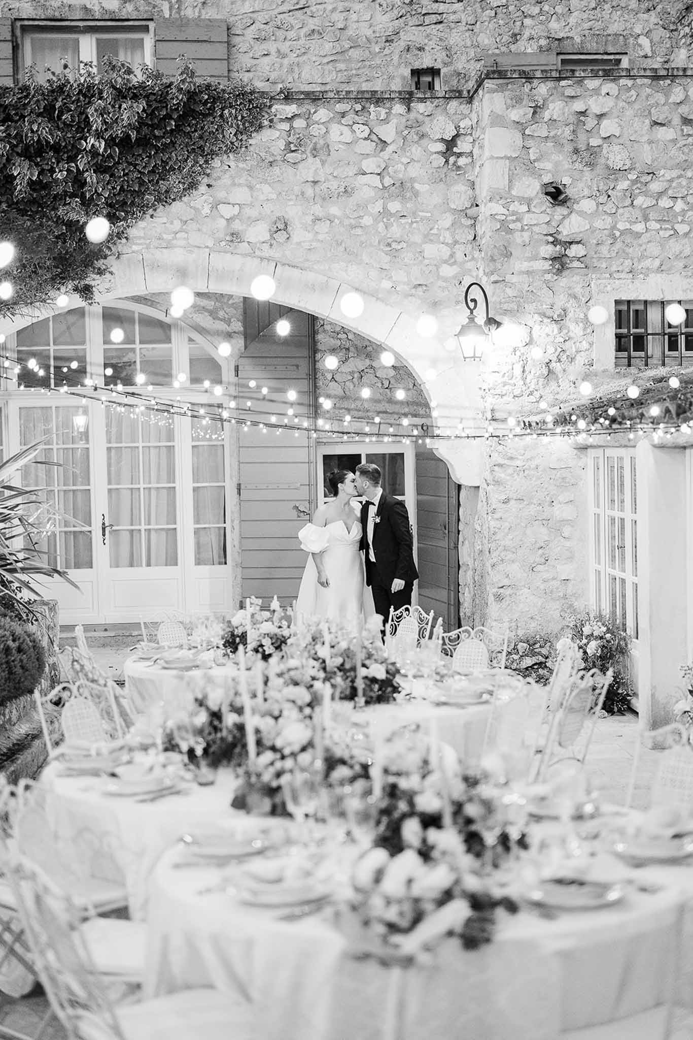 Wedding reception in stone courtyard with string lights and ivy-covered walls