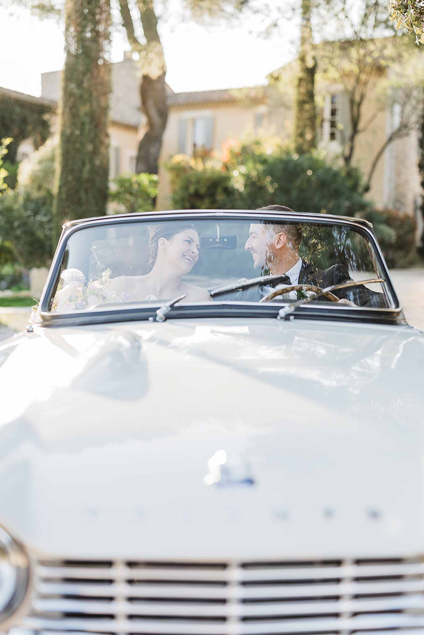 Bride and groom in white convertible car at Mediterranean-style venue courtyard