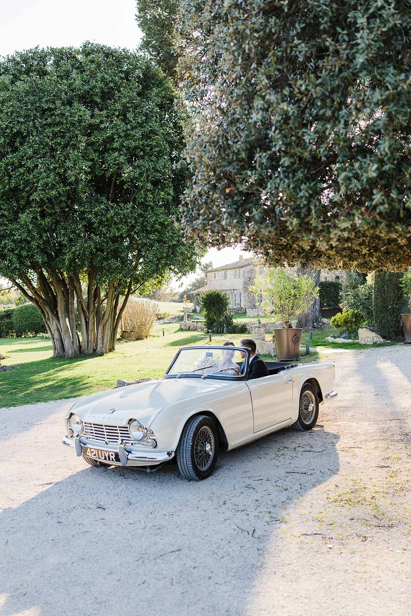 Bride and groom departing in vintage convertible at country estate wedding venue