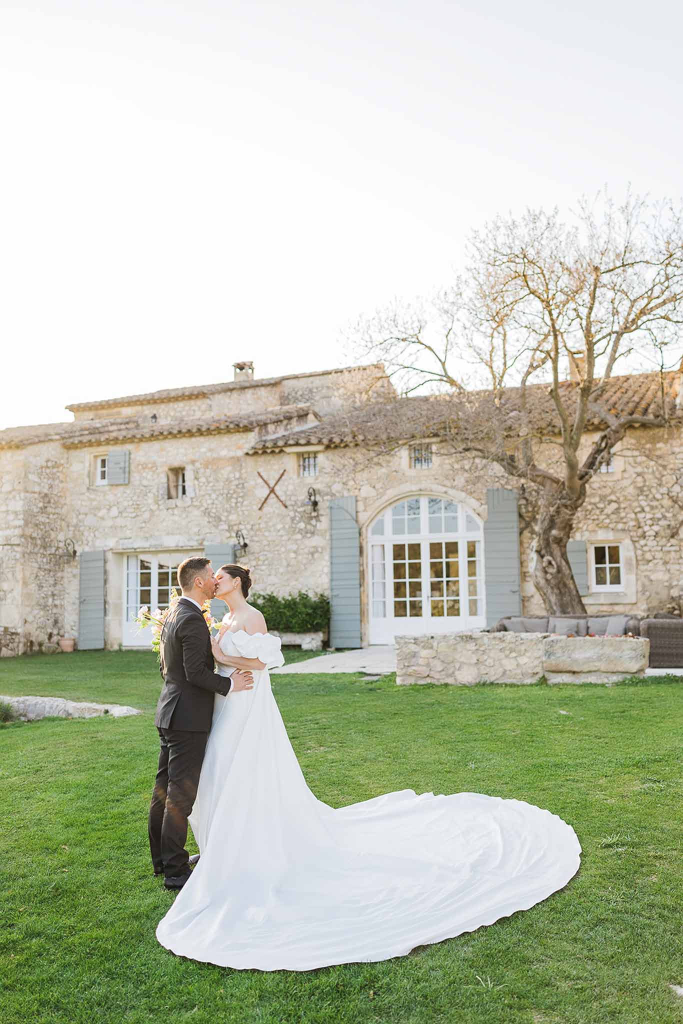 Bride and groom kissing during portrait session at Provençal stone manor with courtyard