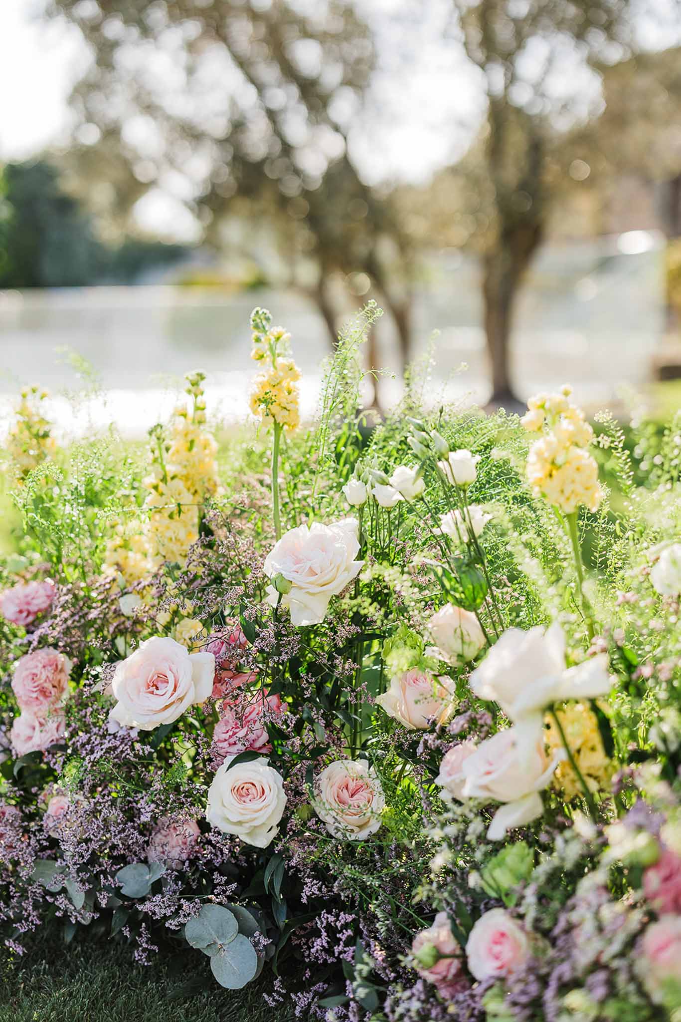 Close-up of romantic floral ceremony backdrop with cream roses and eucalyptus at outdoor wedding venue