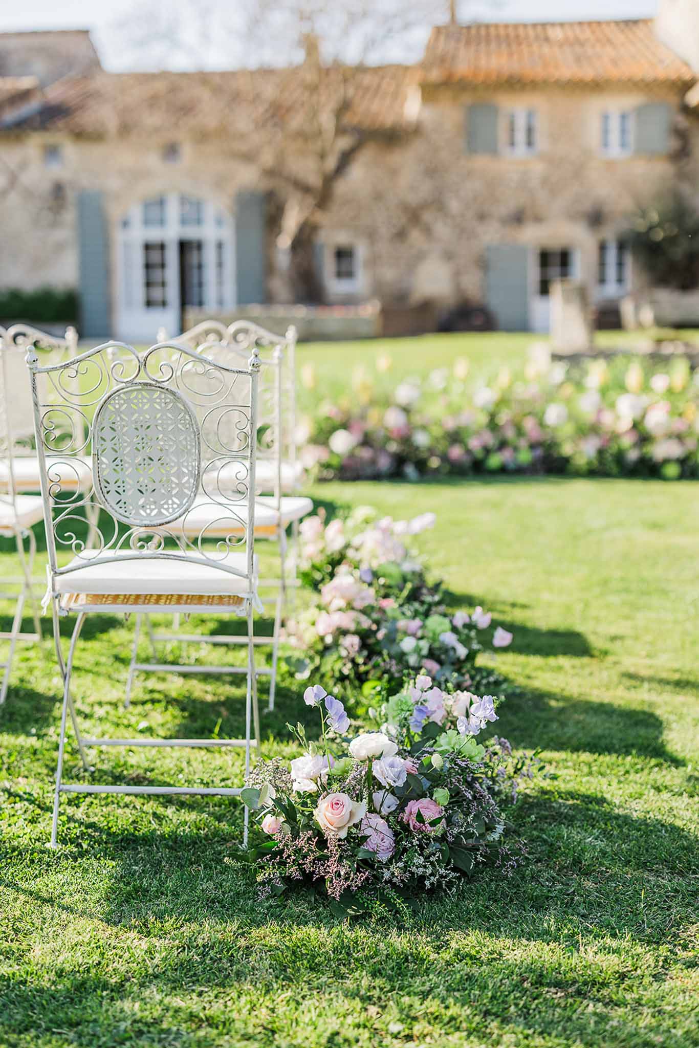 Outdoor ceremony setup with stone chairs in formal garden at country estate with manor house