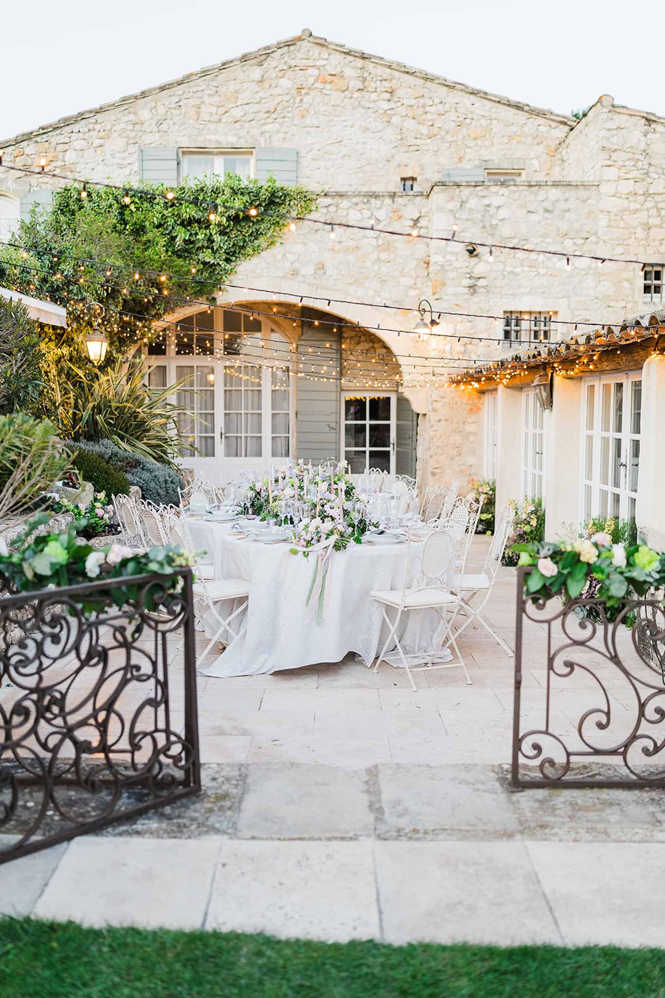 Outdoor wedding reception setup in historic stone courtyard with round tables and string lights