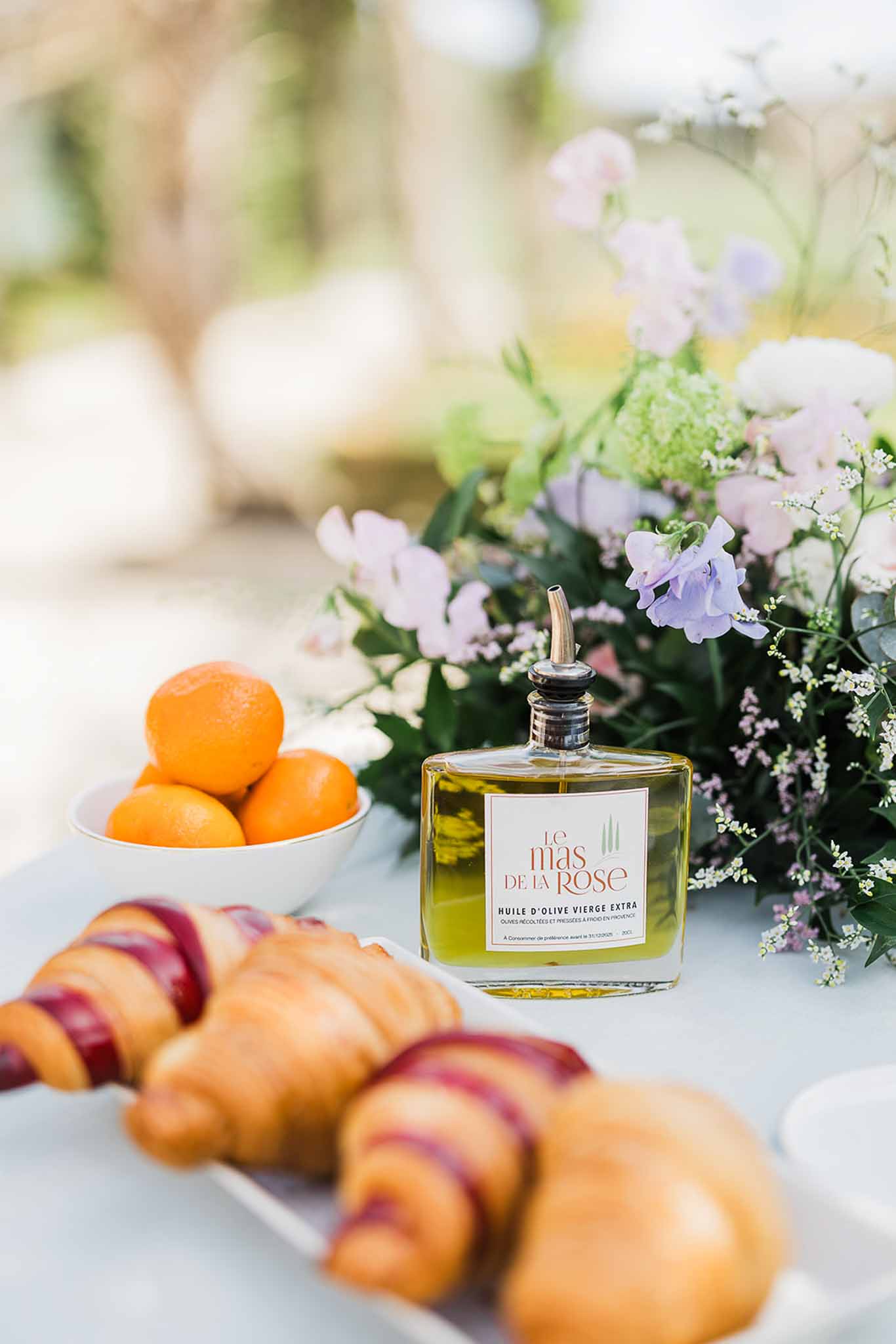 Wedding reception flat lay with croissants, oranges, olive oil and lavender flowers on outdoor terrace