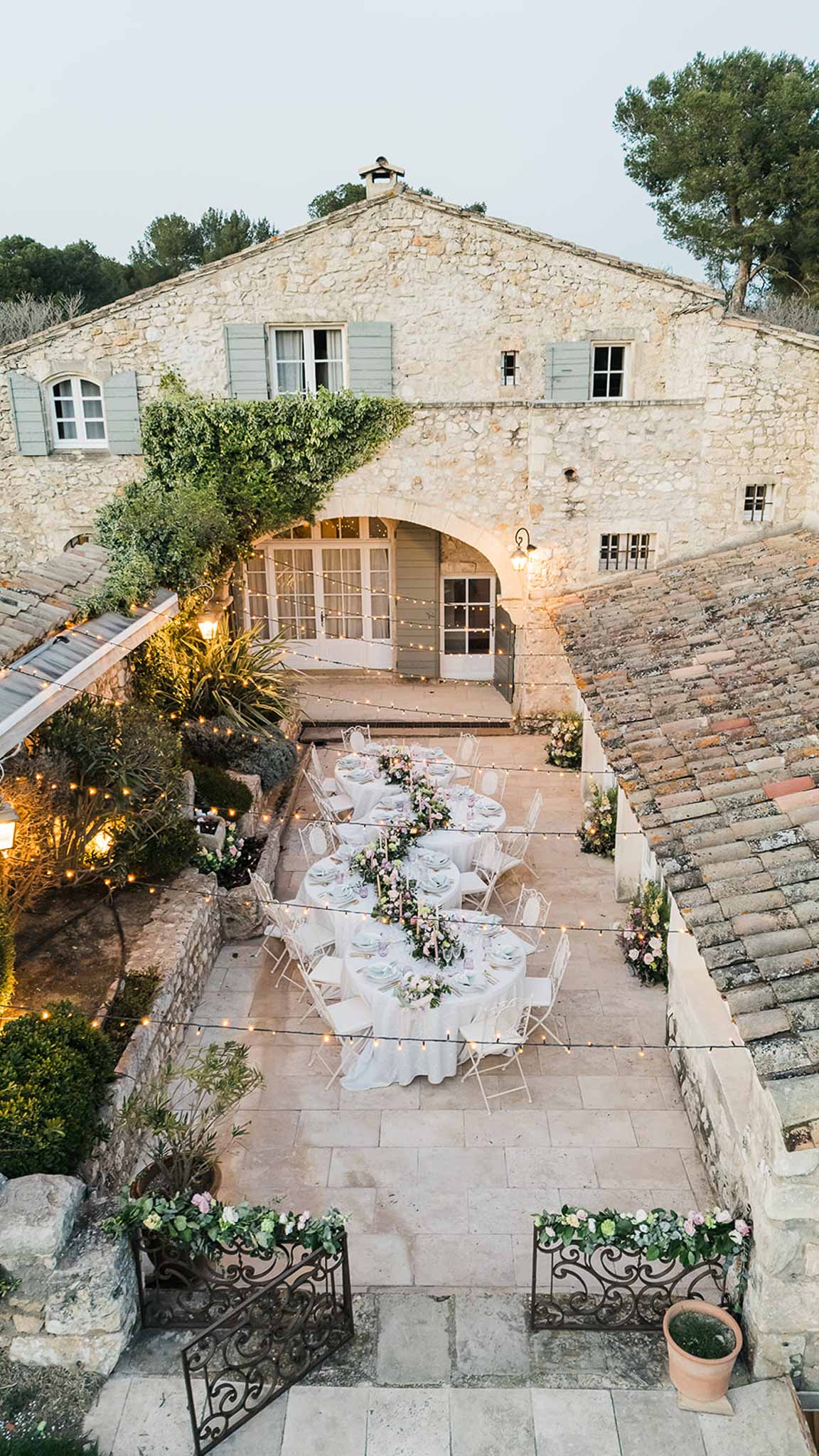 Aerial view of wedding reception dinner setup in historic stone courtyard with Mediterranean architecture