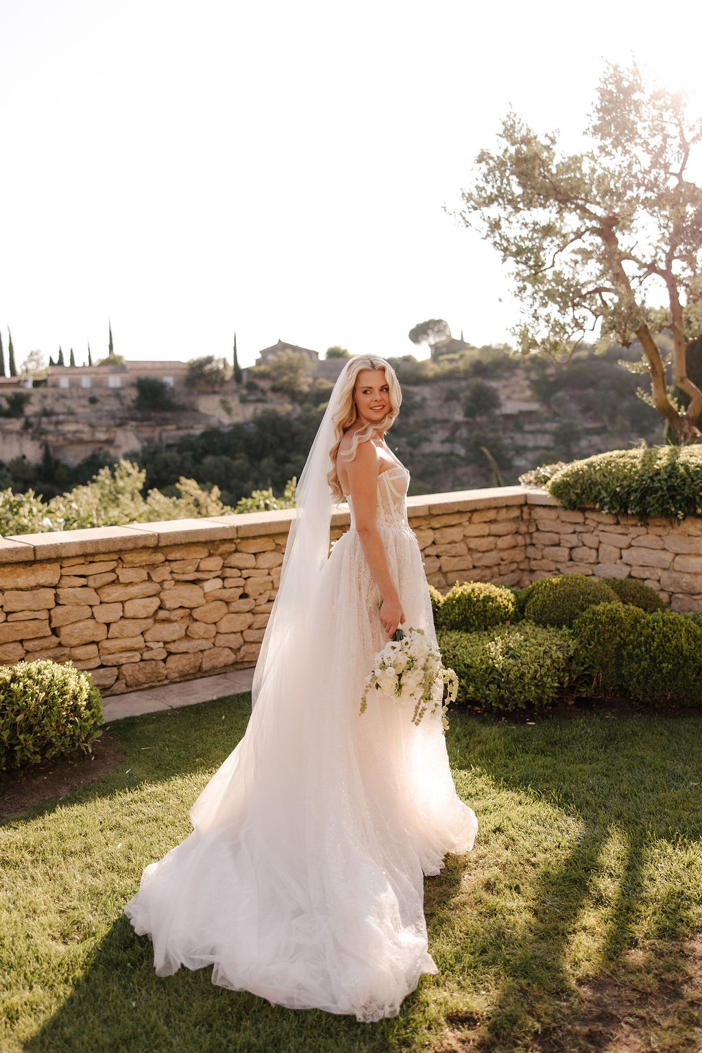 Bride in lace gown with veil and bouquet at Airelles Gordes La Bastide, Provence