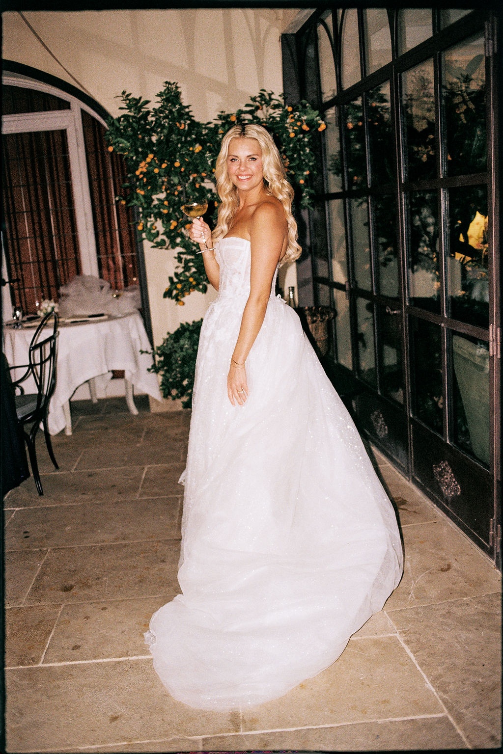 Bride holding champagne glass in courtyard at Airelles Gordes La Bastide, Provence