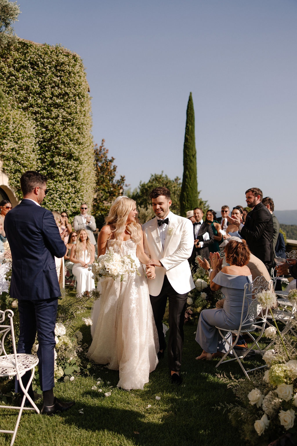 Bride and groom hold hands at ceremony altar at Airelles Gordes La Bastide, Provence