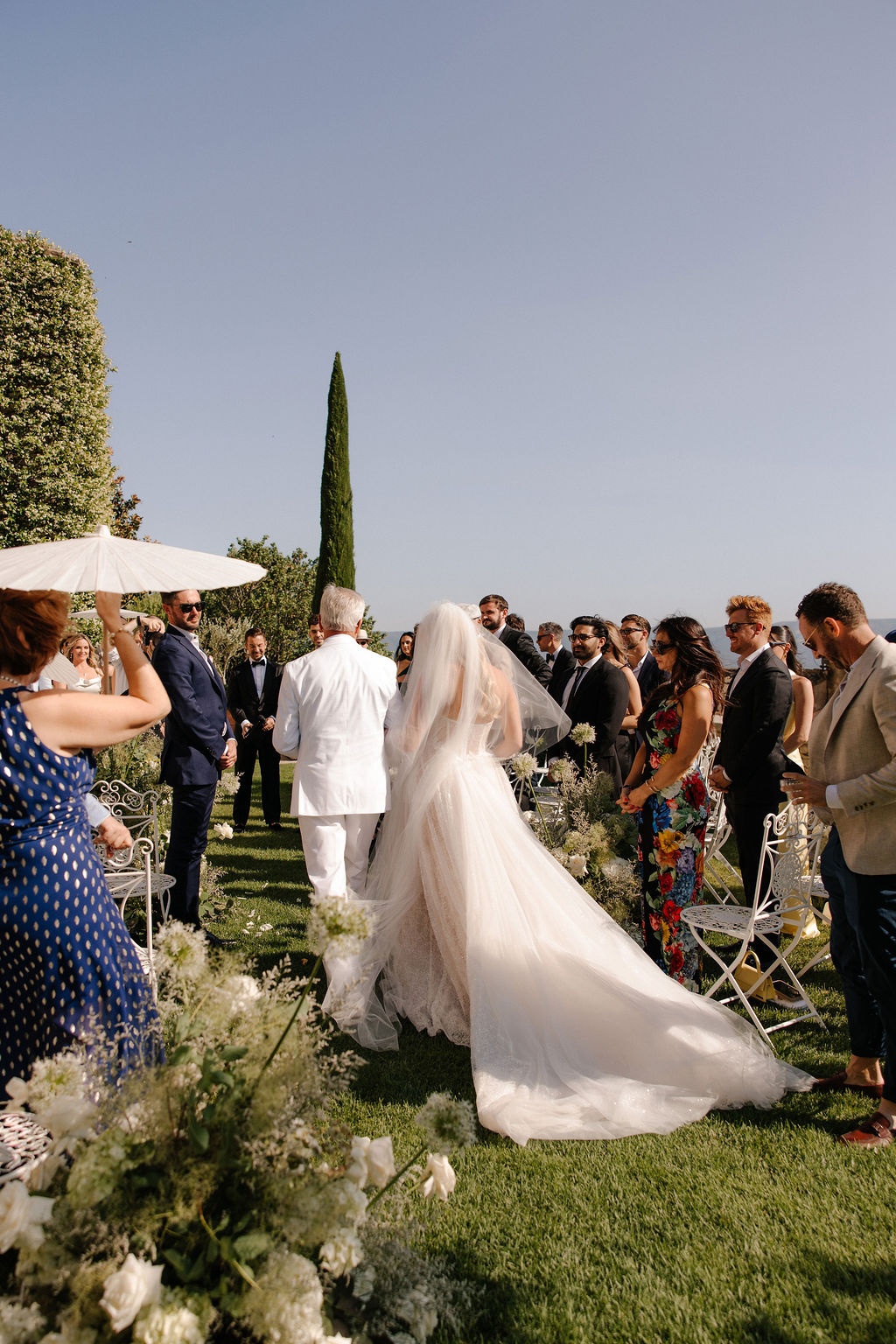 Bride walks down aisle with father from behind at Airelles Gordes La Bastide, Provence