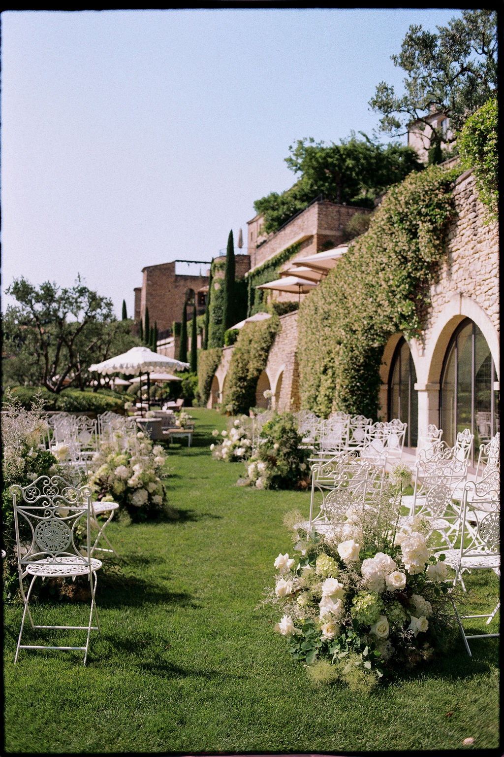 Ceremony aisle with white florals and iron chairs at Airelles Gordes La Bastide, Provence