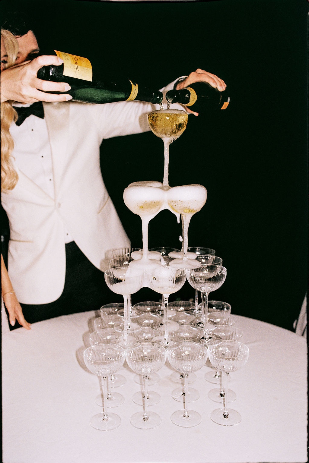 Groom pouring champagne tower at reception at Airelles Gordes La Bastide, Provence