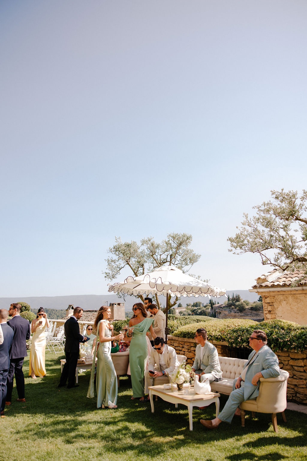 Guests at outdoor cocktail hour under parasol at Airelles Gordes La Bastide, Provence