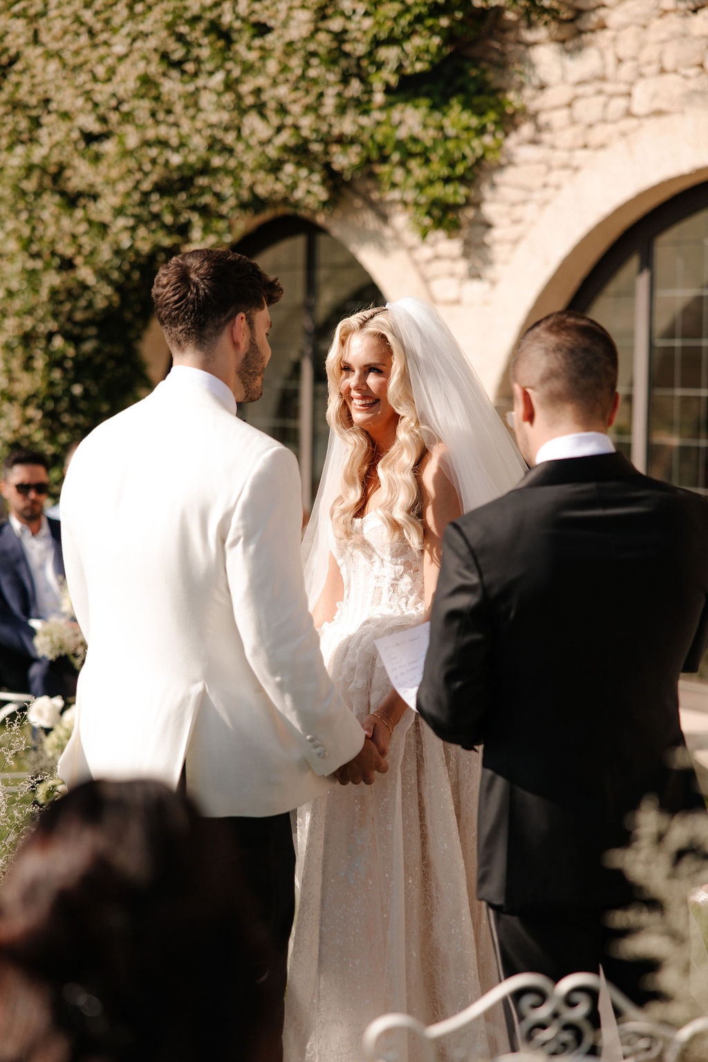 Couple holding hands at ceremony with officiant at Airelles Gordes La Bastide, Provence