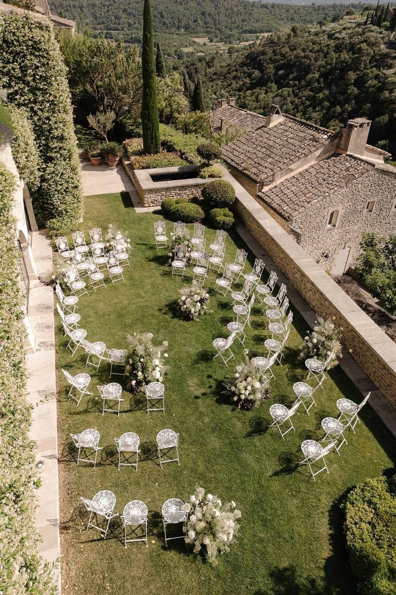 Elevated view of ceremony garden with chairs and stone walls at Airelles Gordes La Bastide